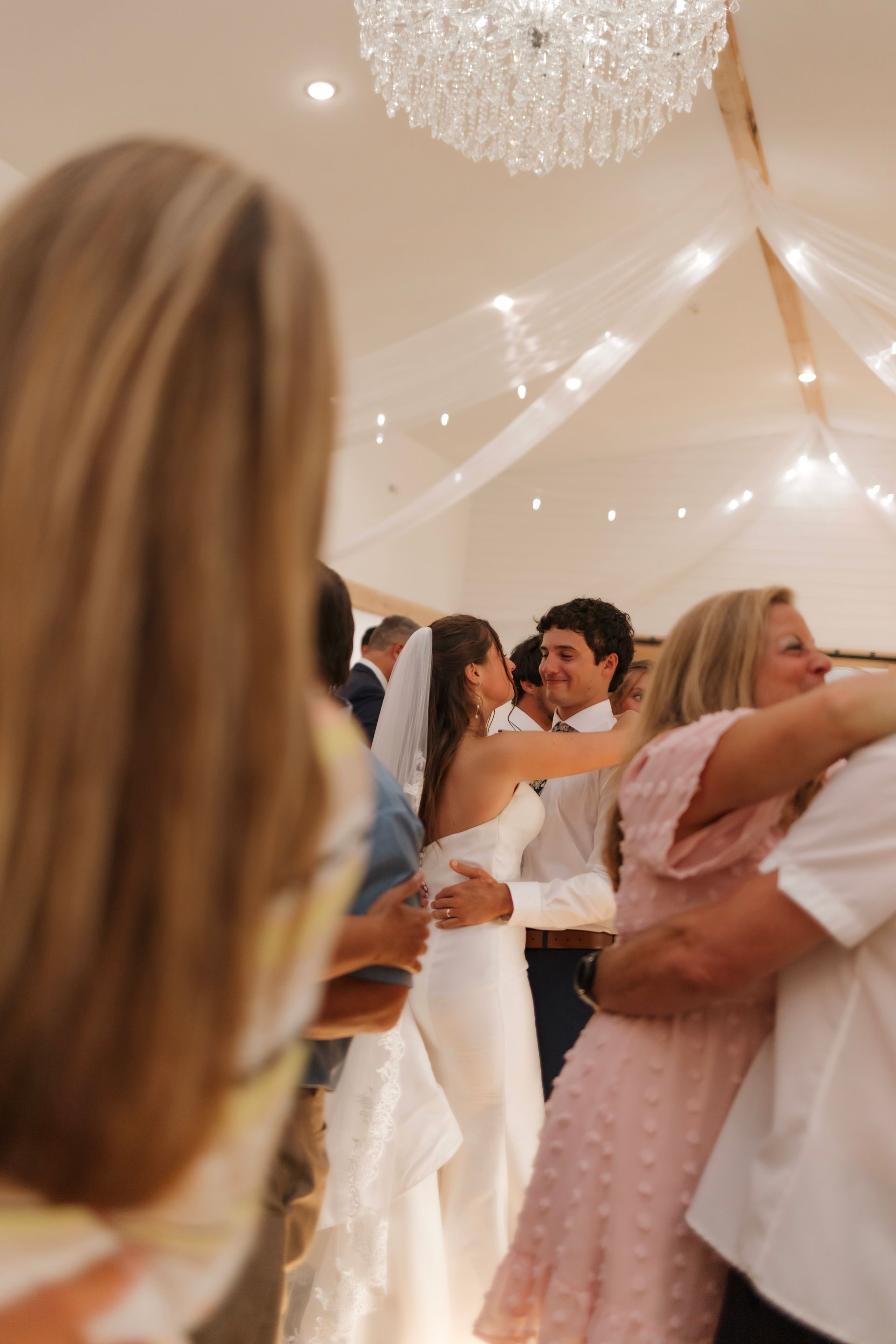 A group of people are dancing at a wedding reception.