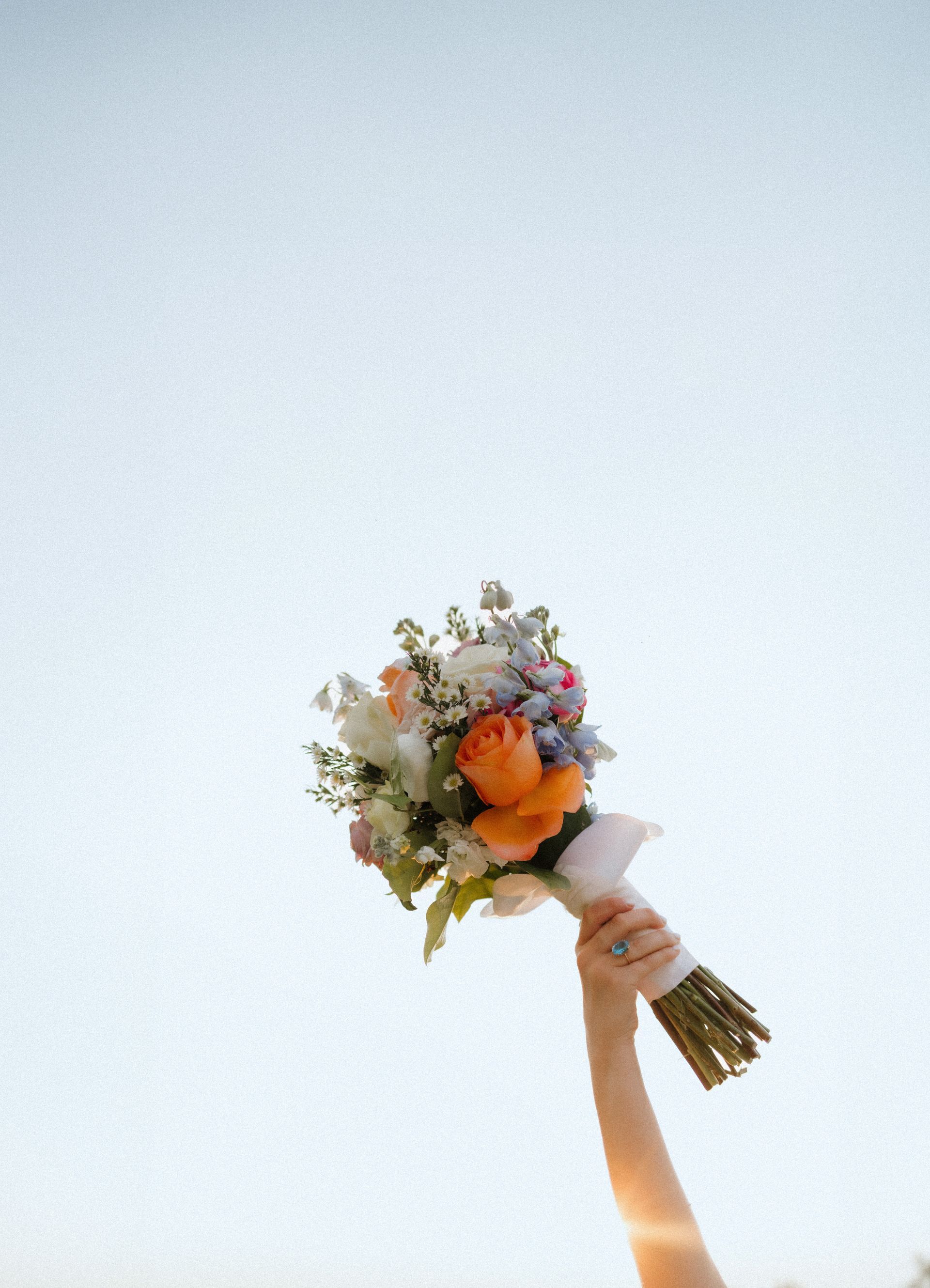 A woman is holding a bouquet of flowers in the air.