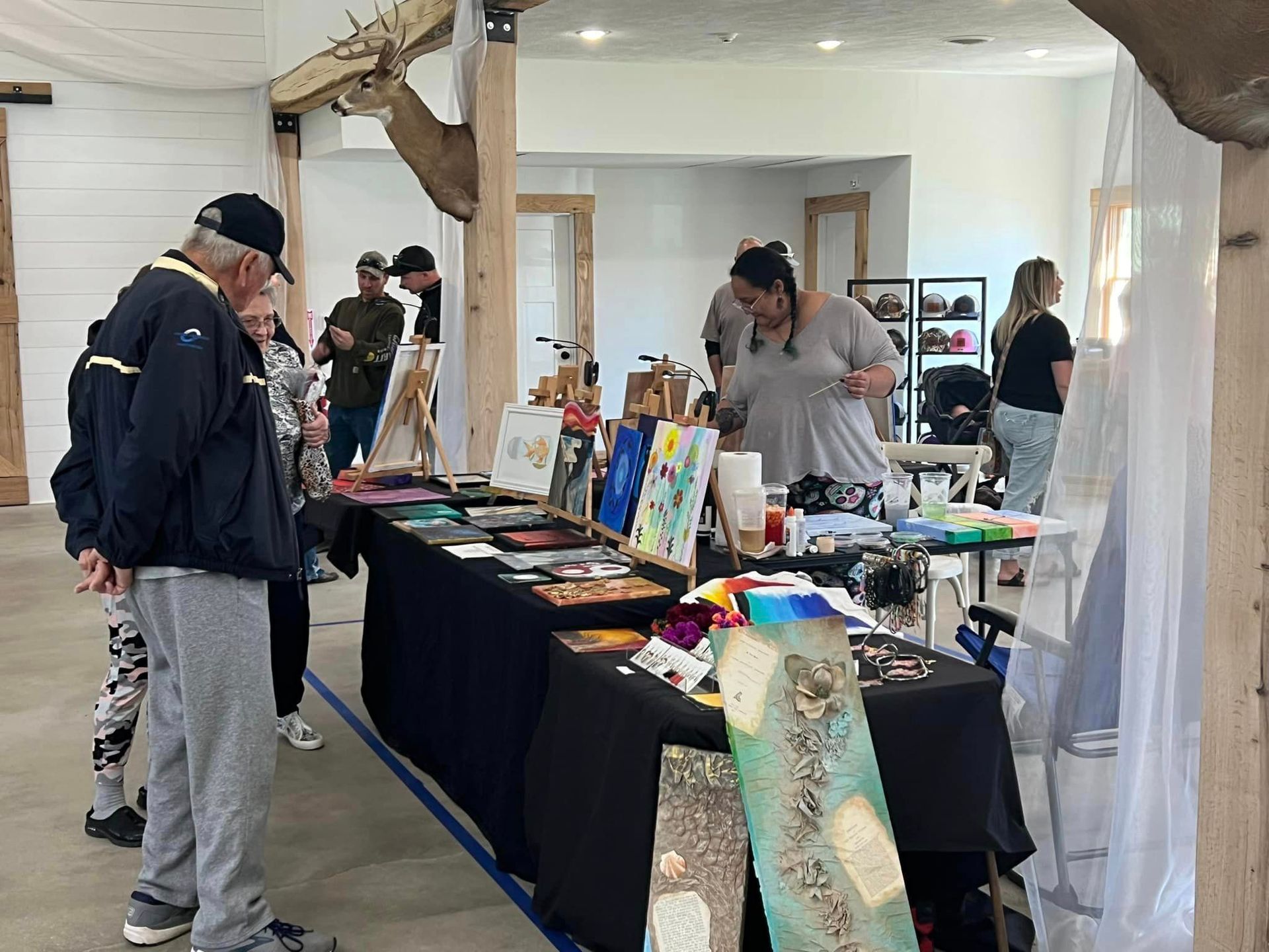 A group of people are standing around a table with paintings on it.