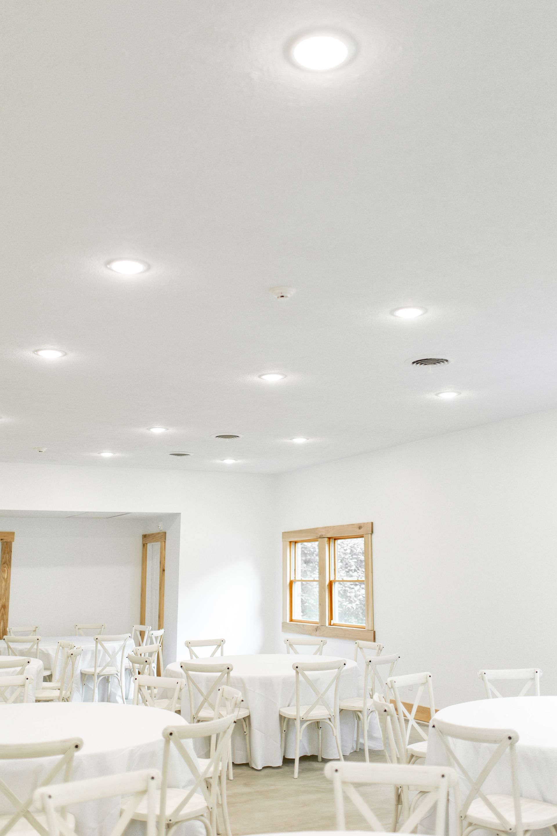 A large room with tables and chairs set up for a wedding reception.