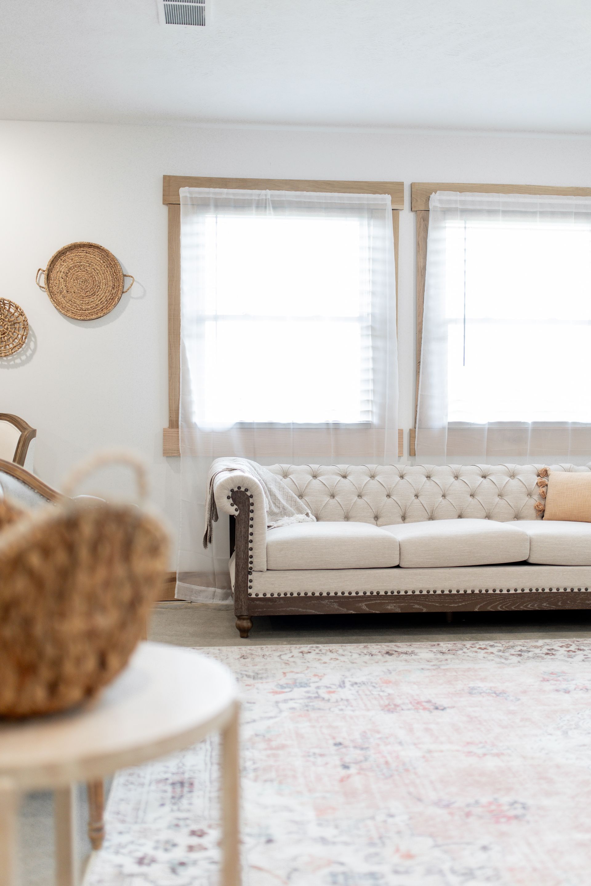 A living room with a white couch and two windows.