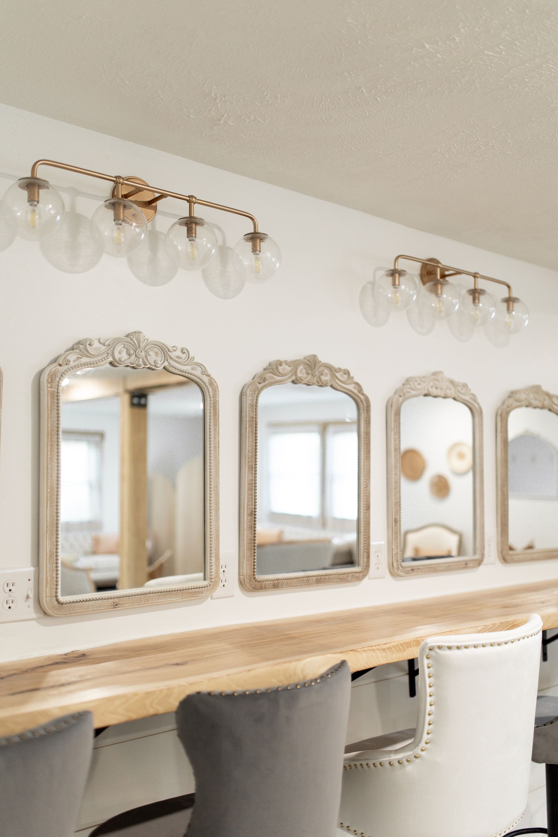 A room with a long wooden table and chairs and mirrors on the wall.