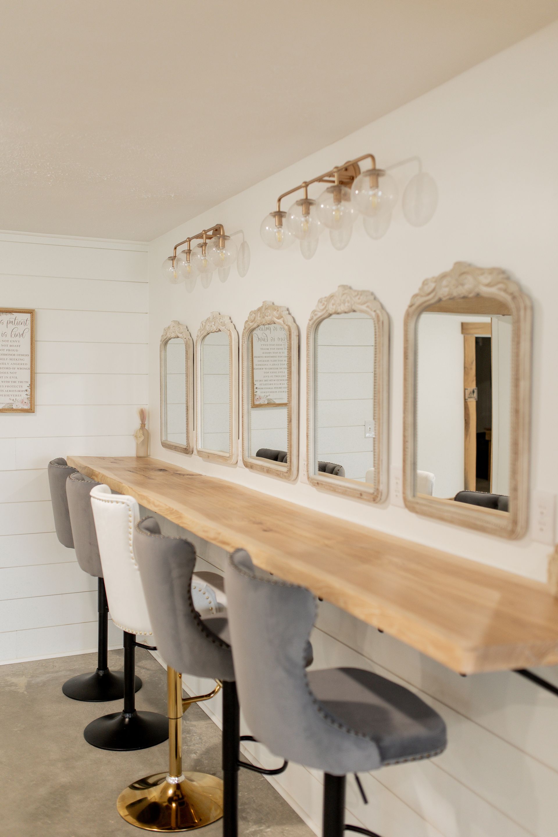 A room with a long wooden table and chairs and mirrors on the wall.