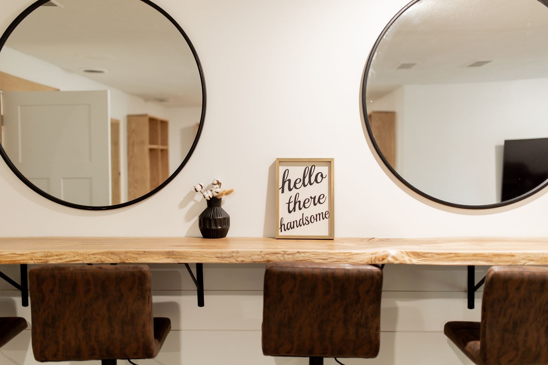 Two chairs are sitting in front of a wooden table with two mirrors.