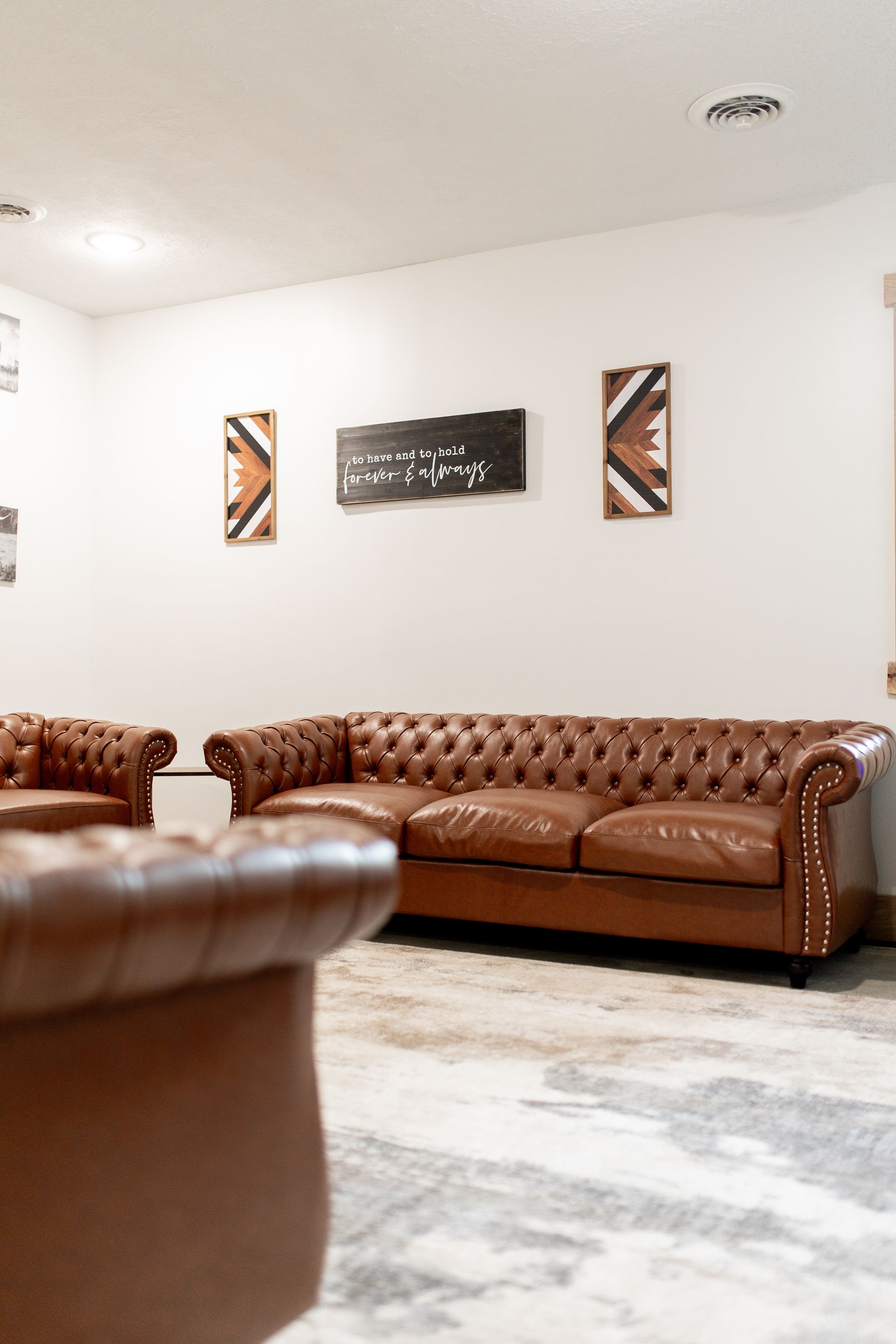 A living room with a brown leather couch and two chairs.