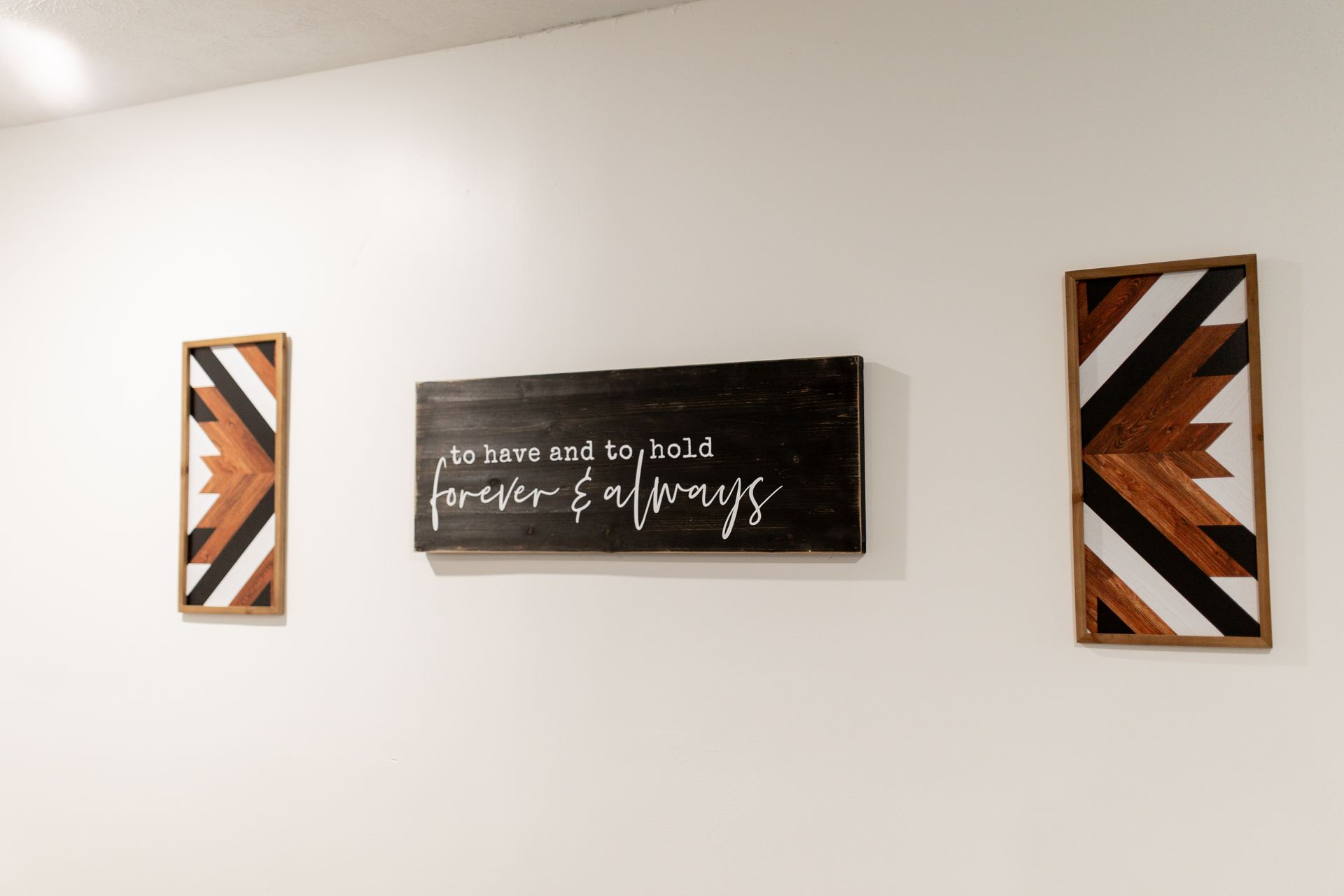 A white wall with three wooden signs hanging on it.