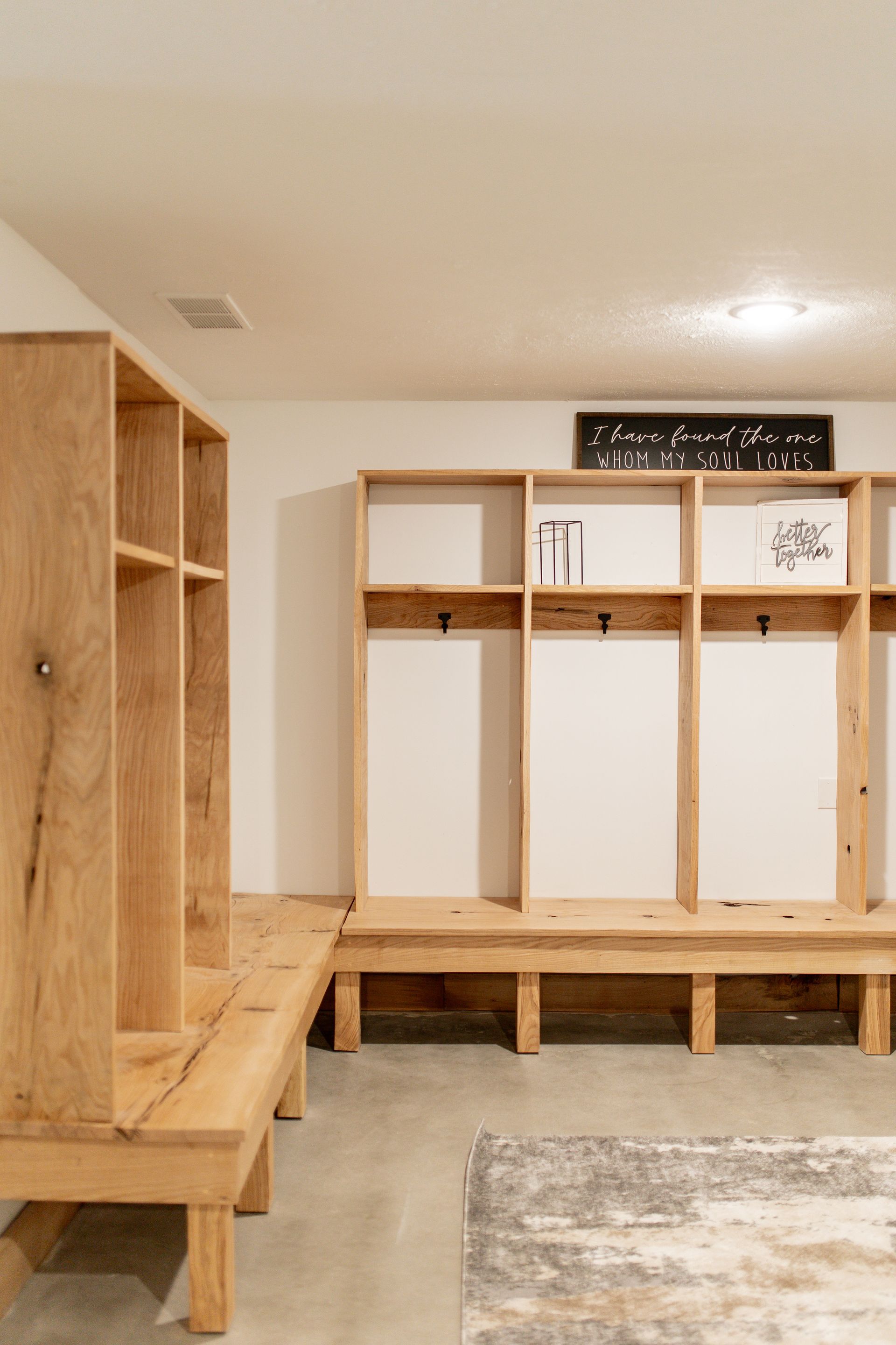 A locker room with wooden shelves and benches and a rug.