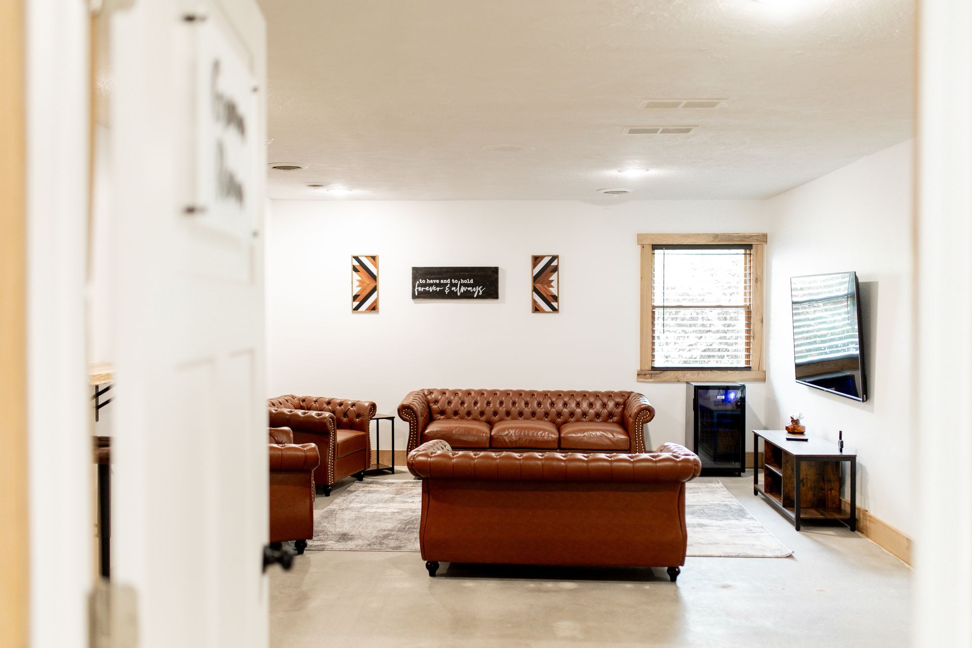 A living room with a brown couch , chairs , and a flat screen tv.