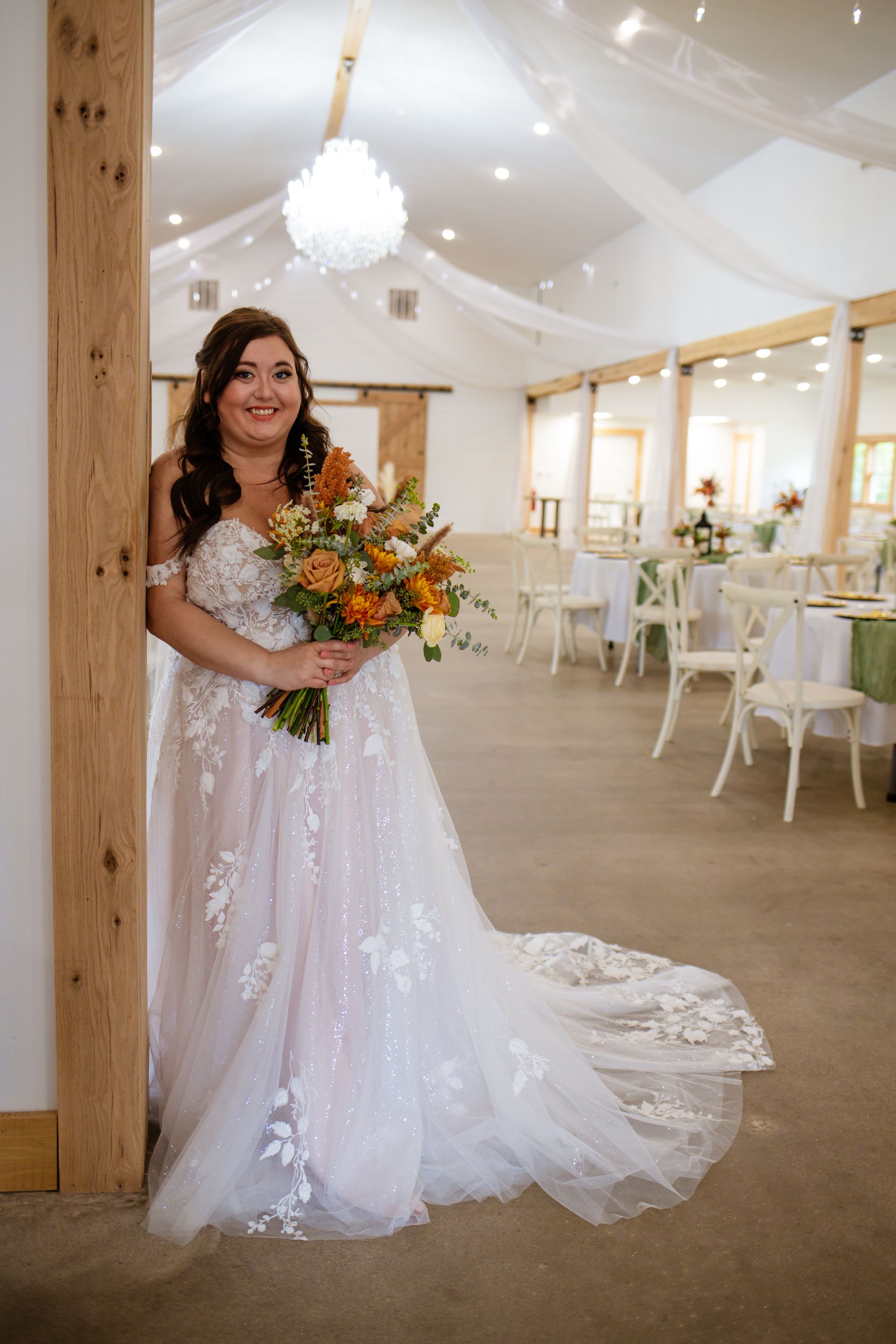 A bride in a wedding dress is standing in a room holding a bouquet of flowers.