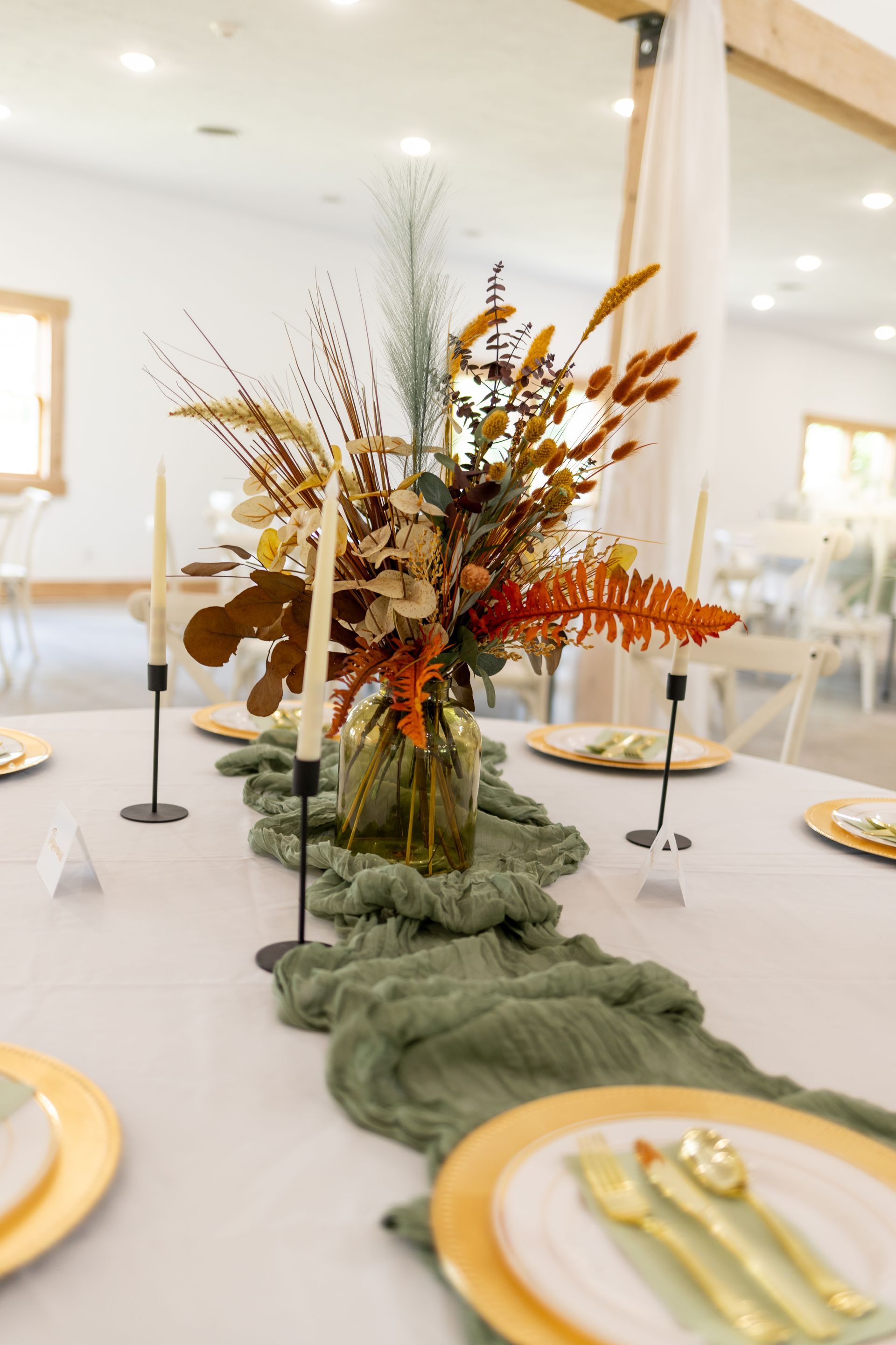 A table with a vase of flowers and candles on it.