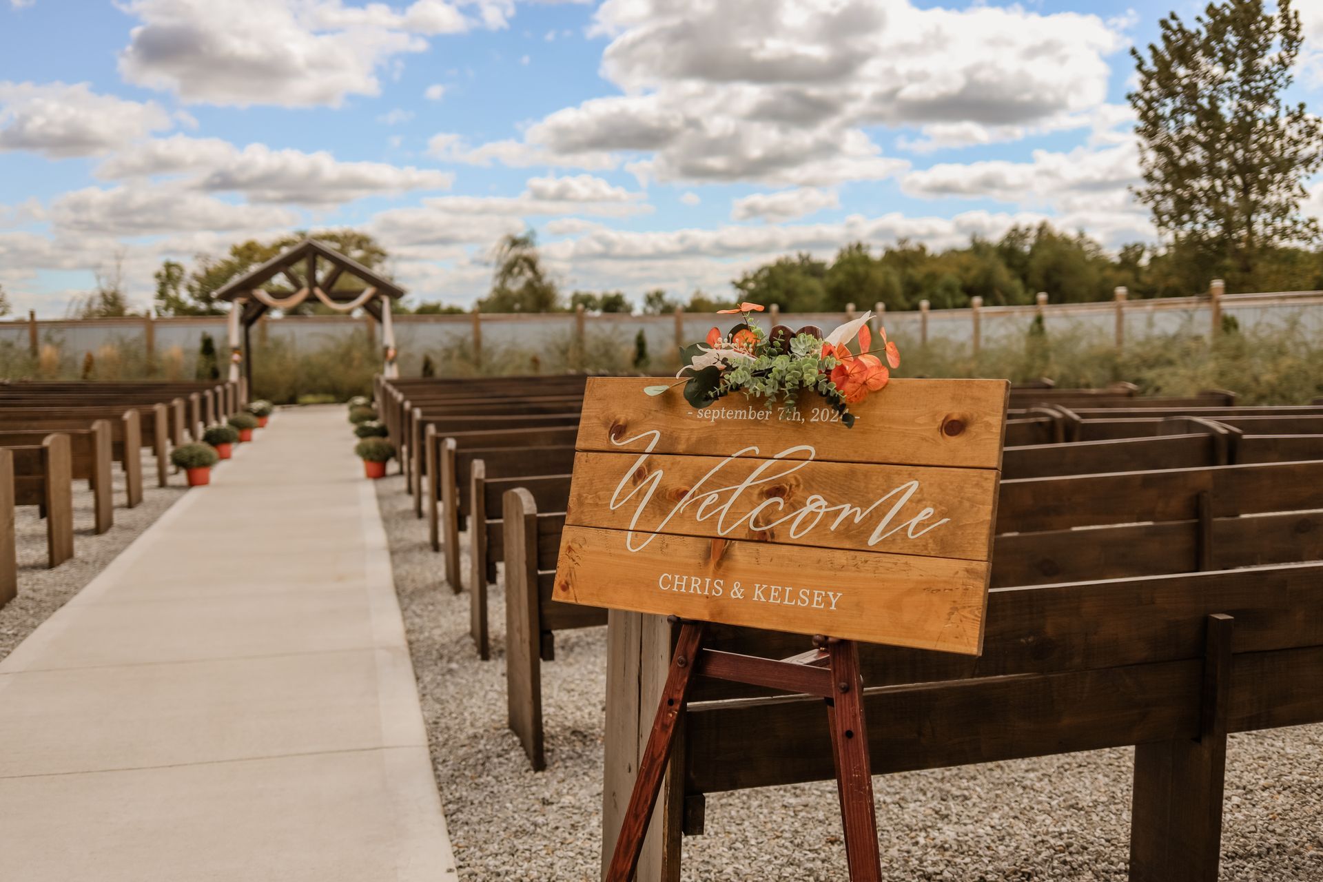 A wooden welcome sign is sitting in front of a row of wooden benches.
