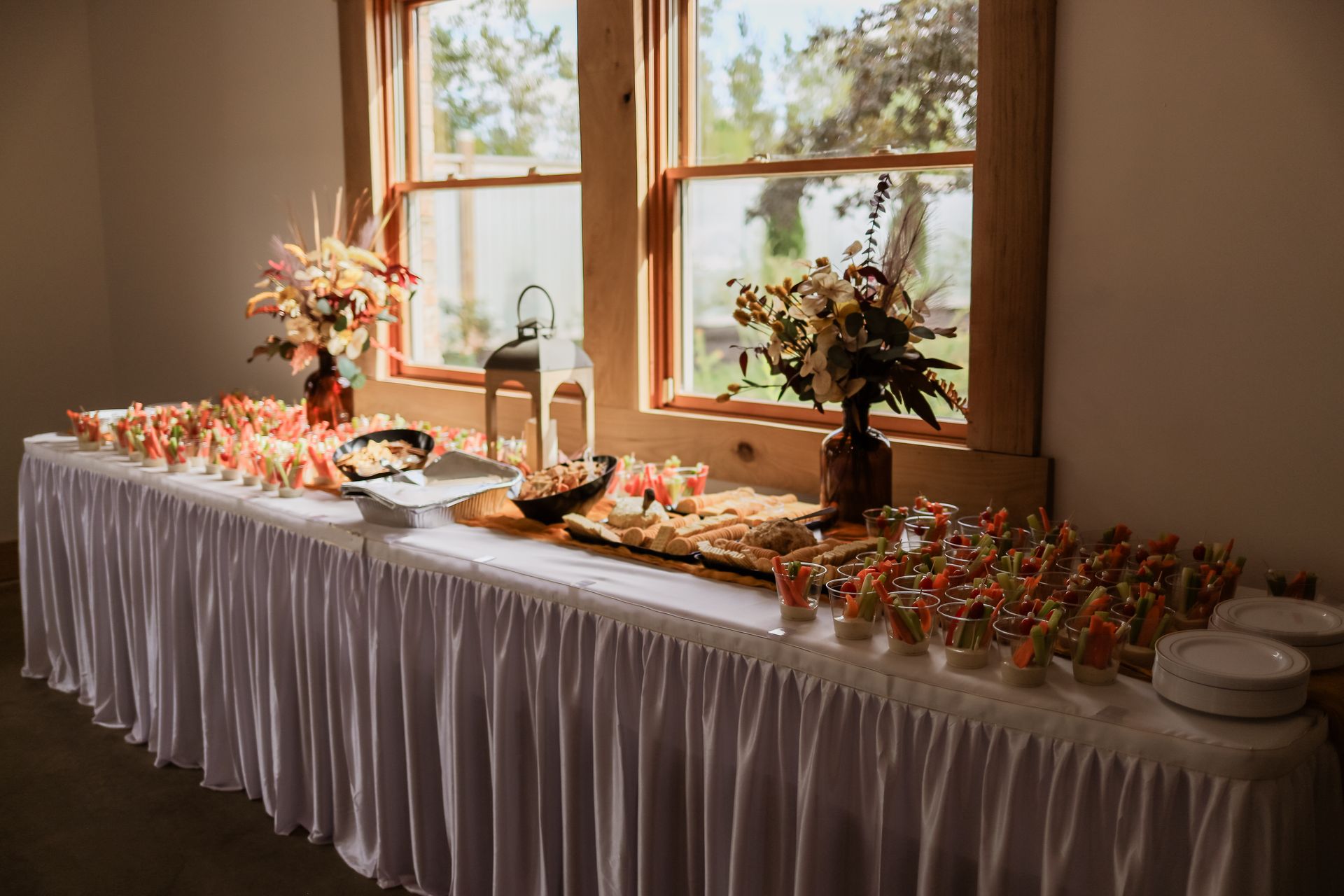 A long table with a white table cloth is sitting in front of a window.
