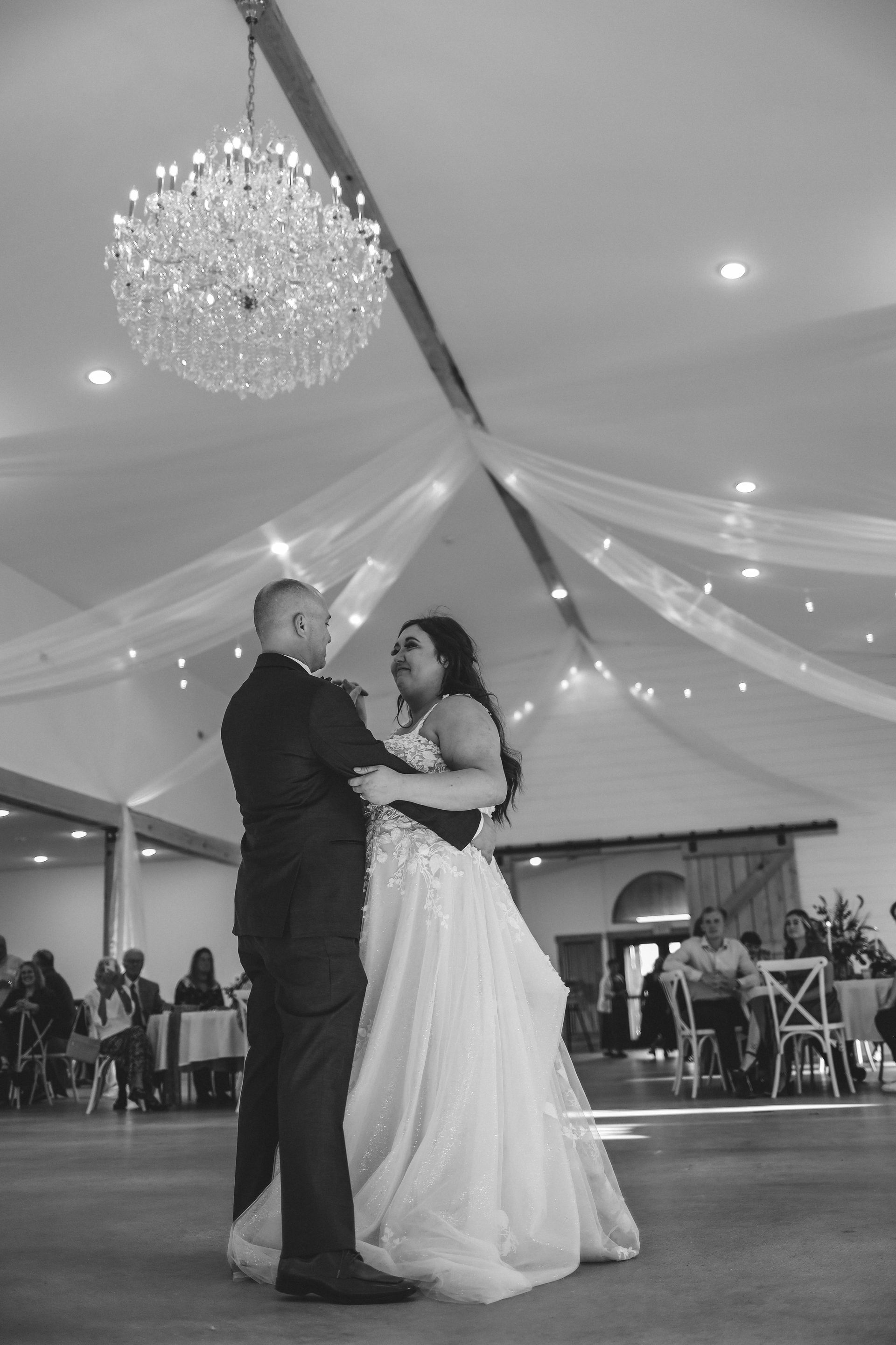 A black and white photo of a bride and groom dancing at their wedding reception.