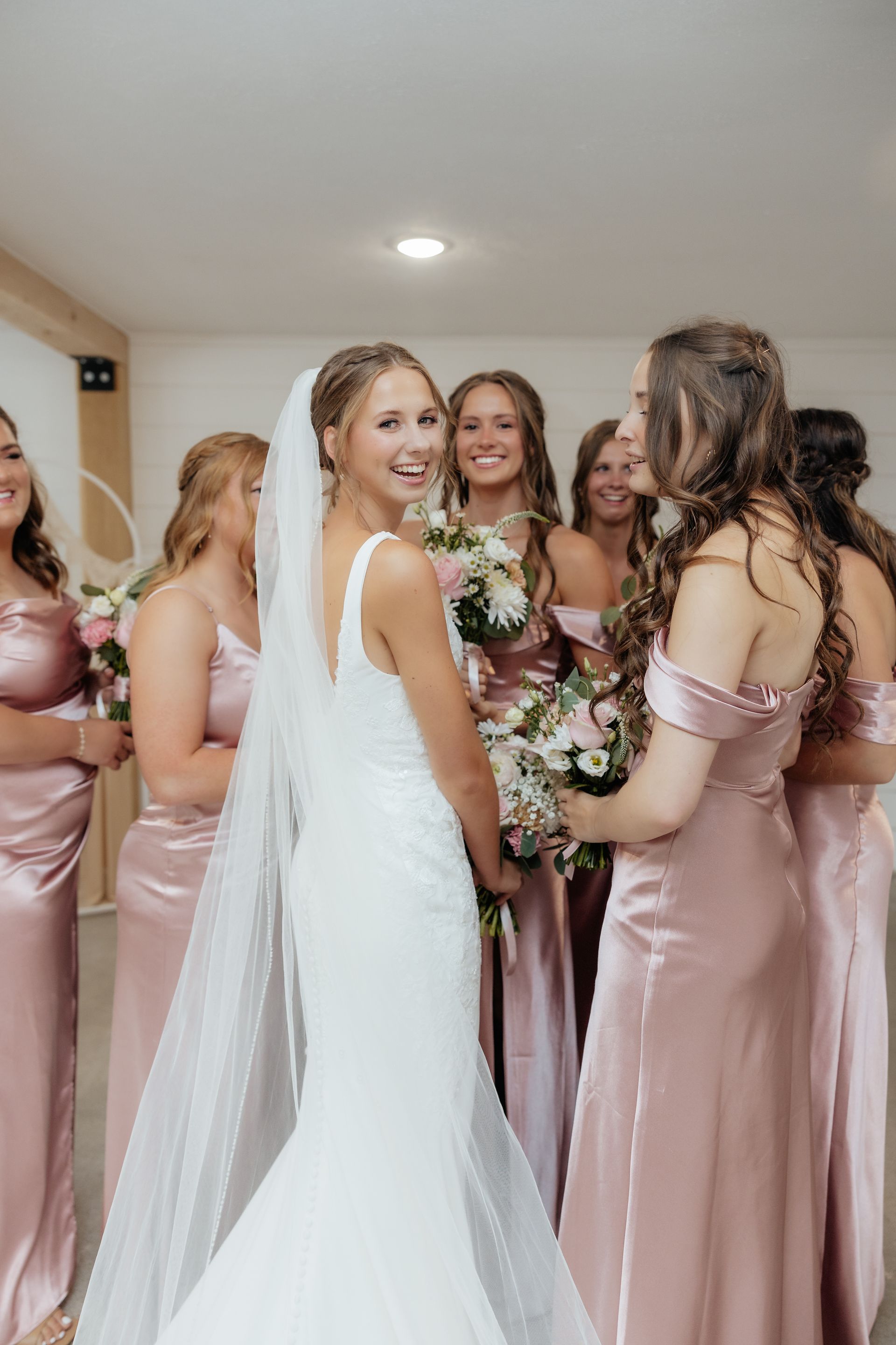 A bride and her bridesmaids are standing next to each other in a room.