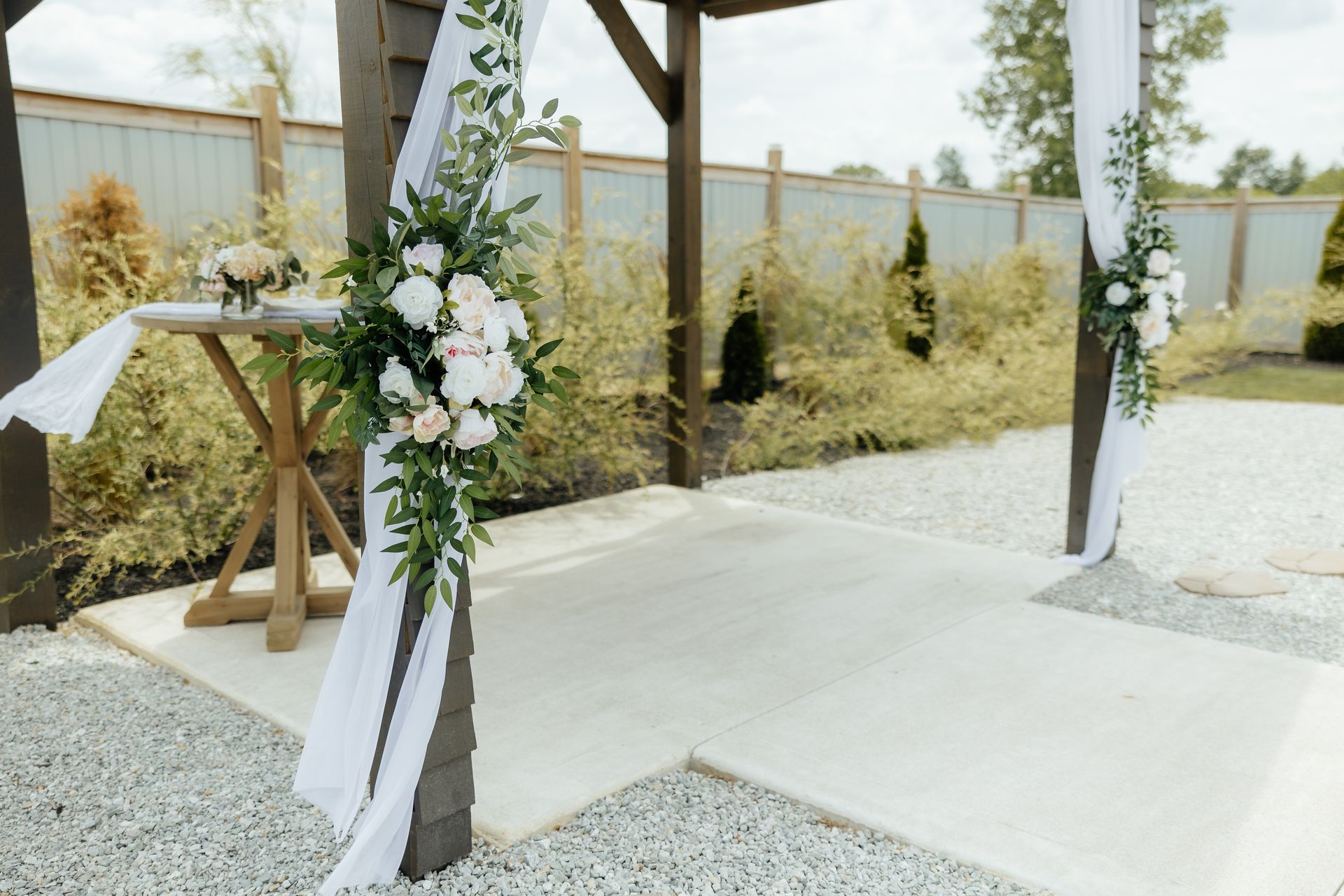 A gazebo decorated with white flowers and greenery for a wedding ceremony.