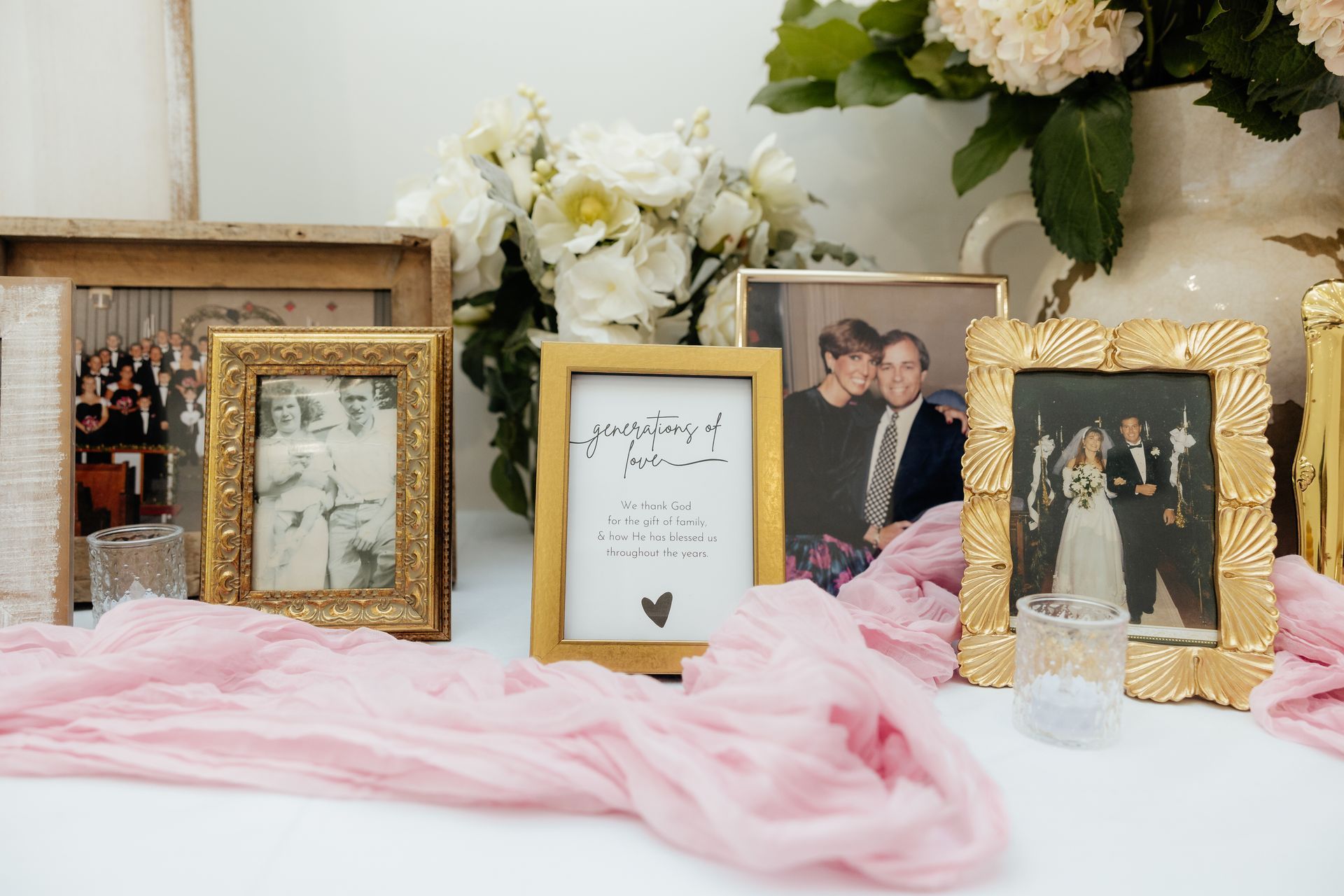 A table with a vase of flowers and a bunch of pictures on it.