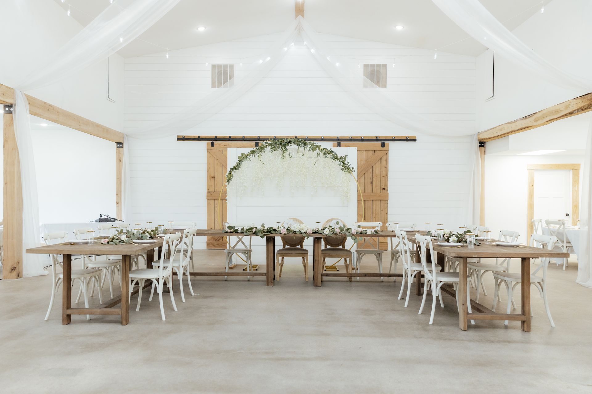A large room with tables and chairs set up for a wedding reception.