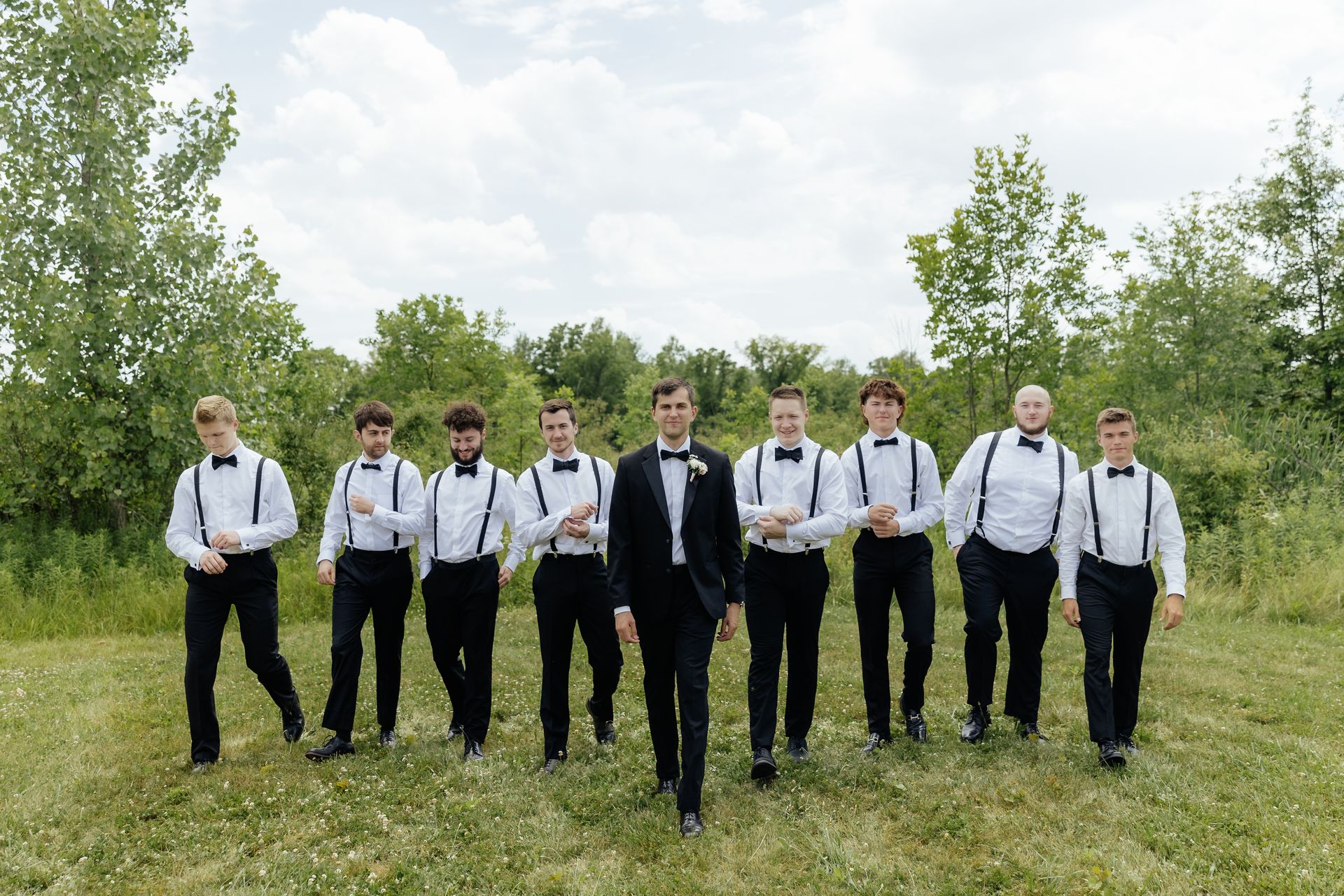 A groom and his groomsmen are posing for a picture in a field.