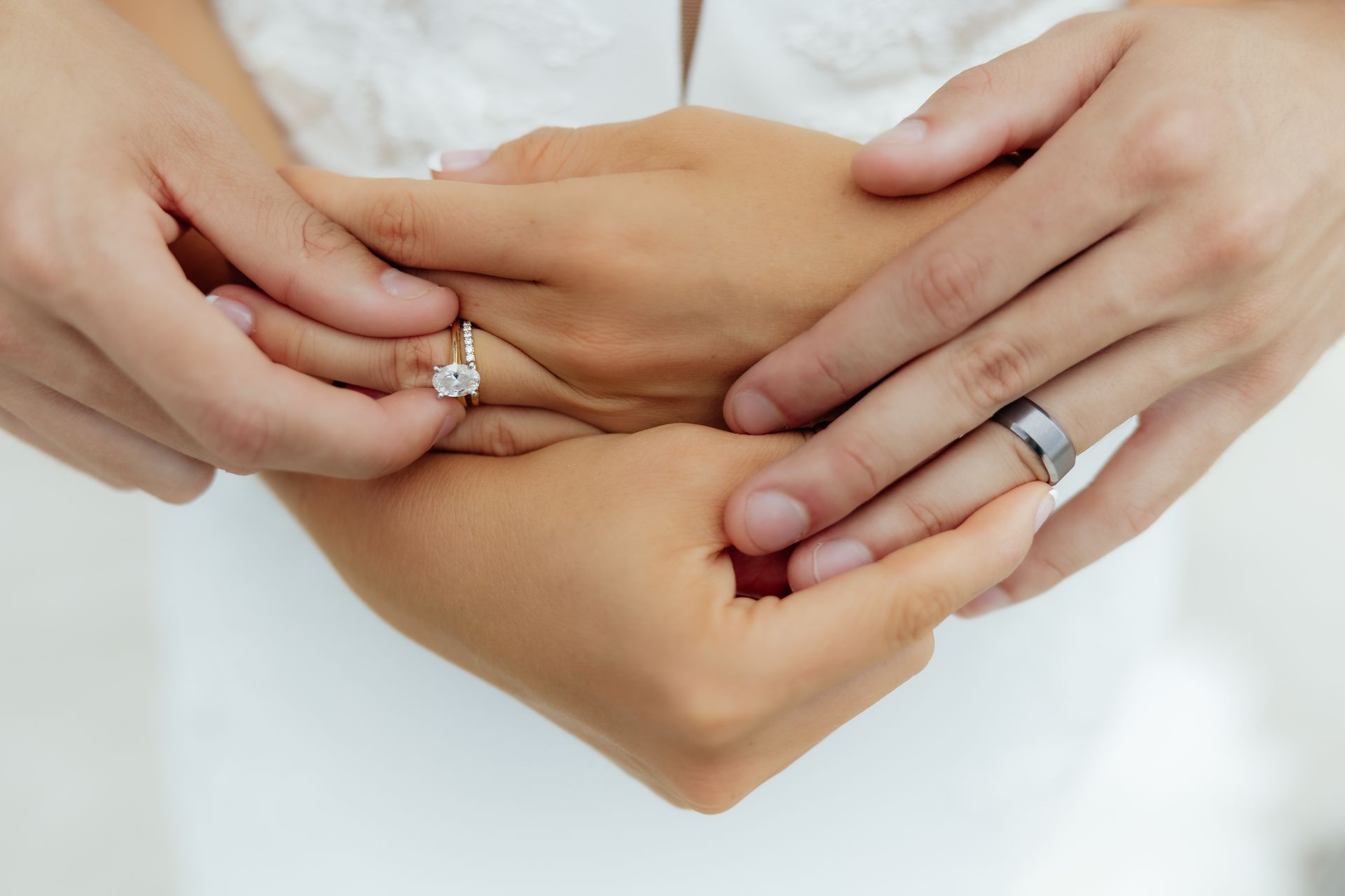 A man and a woman are holding each other 's hands with their wedding rings on.