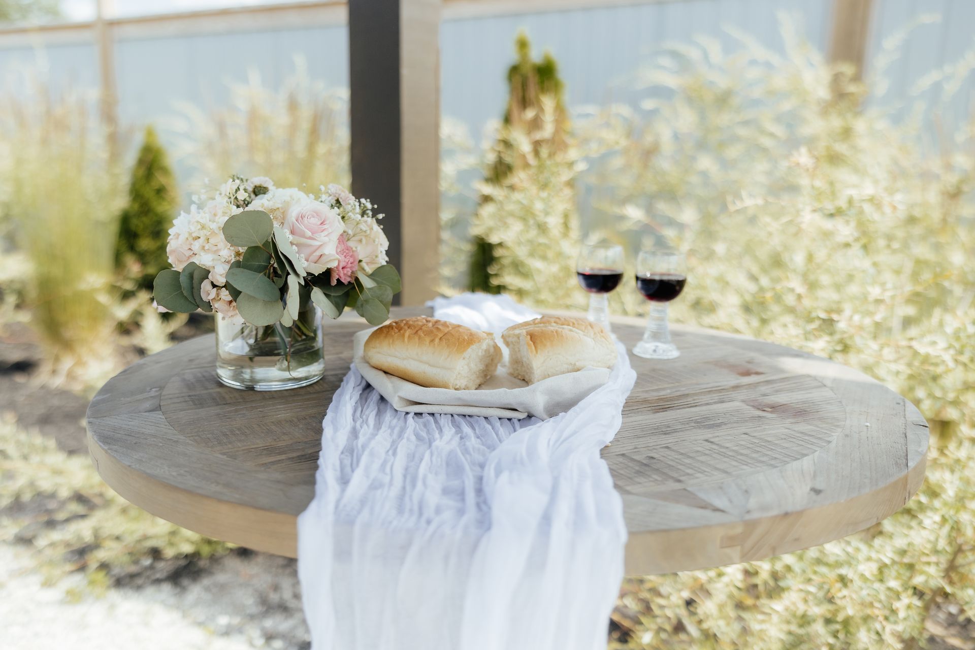 A wooden table with a loaf of bread and two glasses of wine on it.