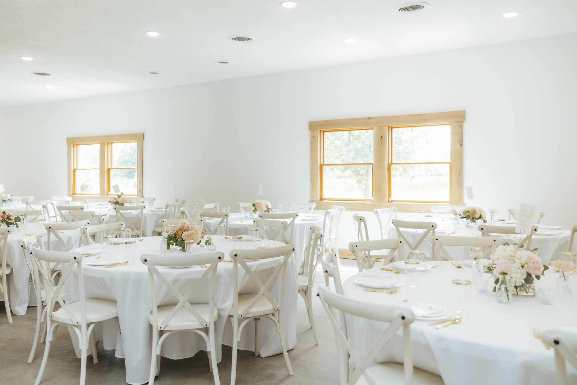 A room filled with tables and chairs set up for a wedding reception.