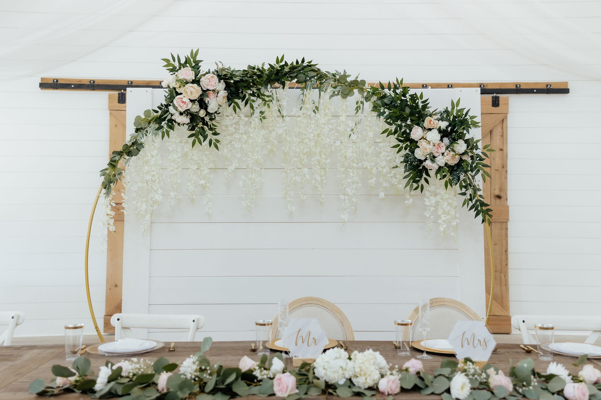 A table with flowers and a sliding barn door in the background.