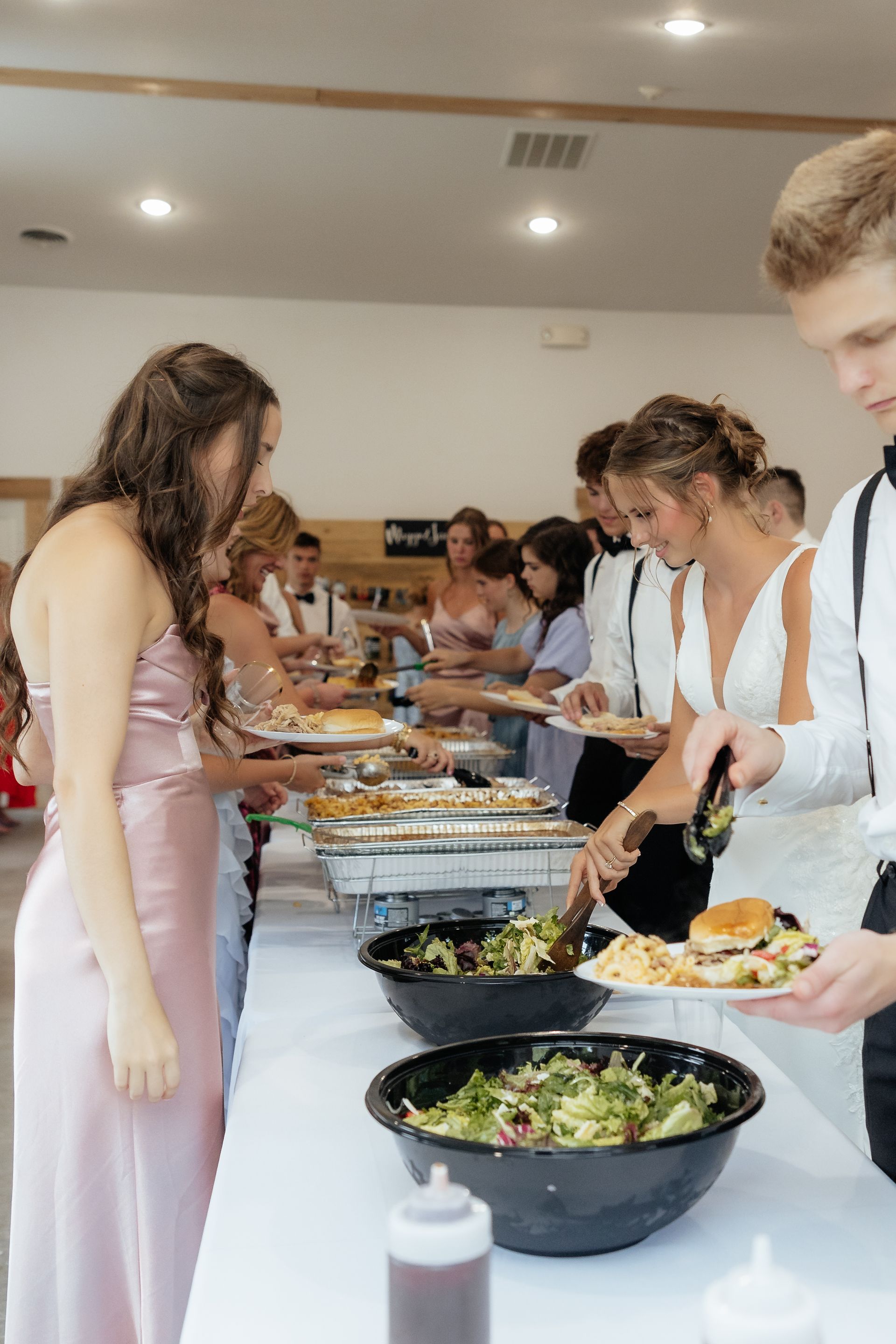 A group of people are standing at a buffet table eating food.