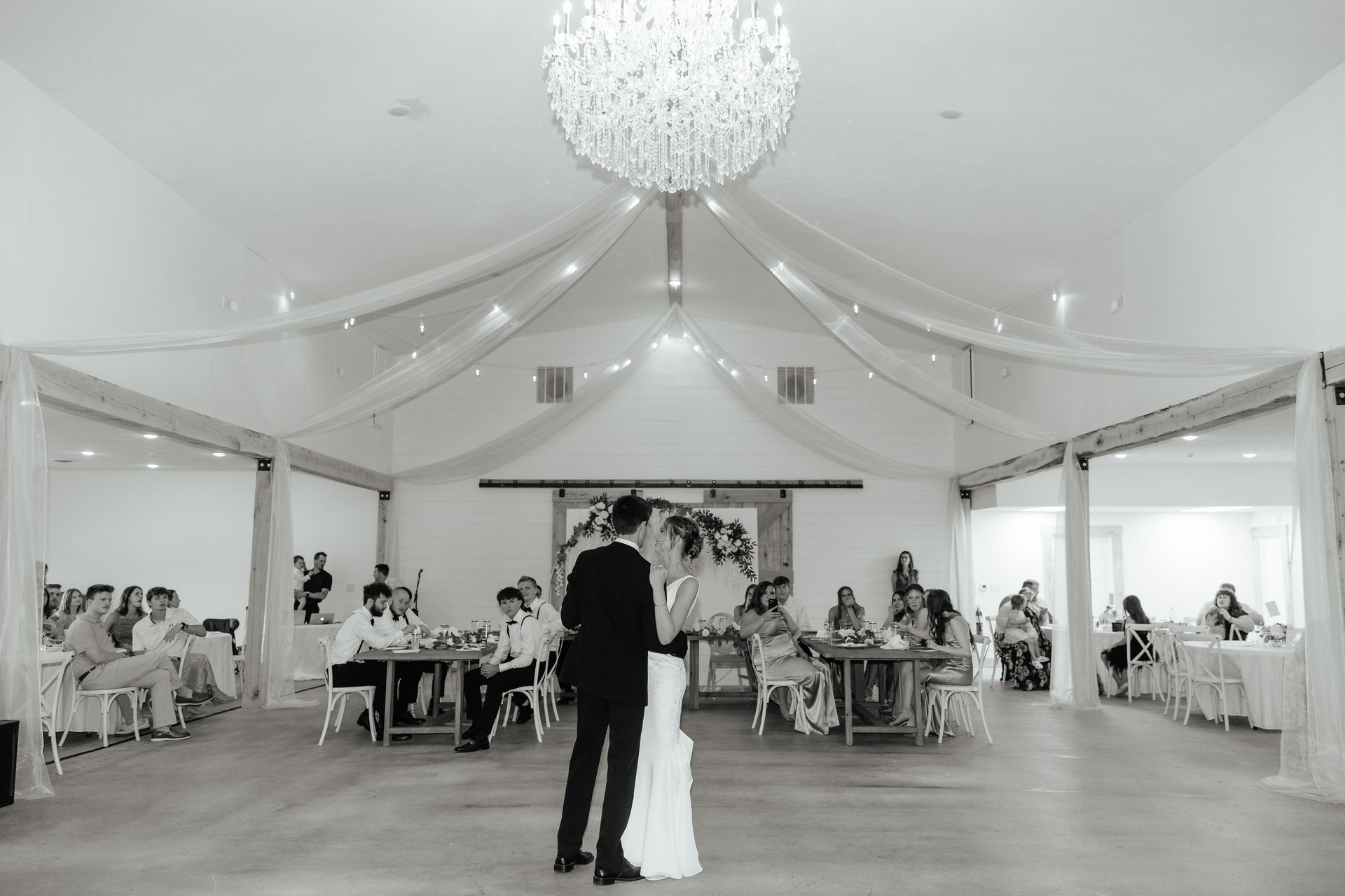 A black and white photo of a bride and groom dancing at their wedding reception.