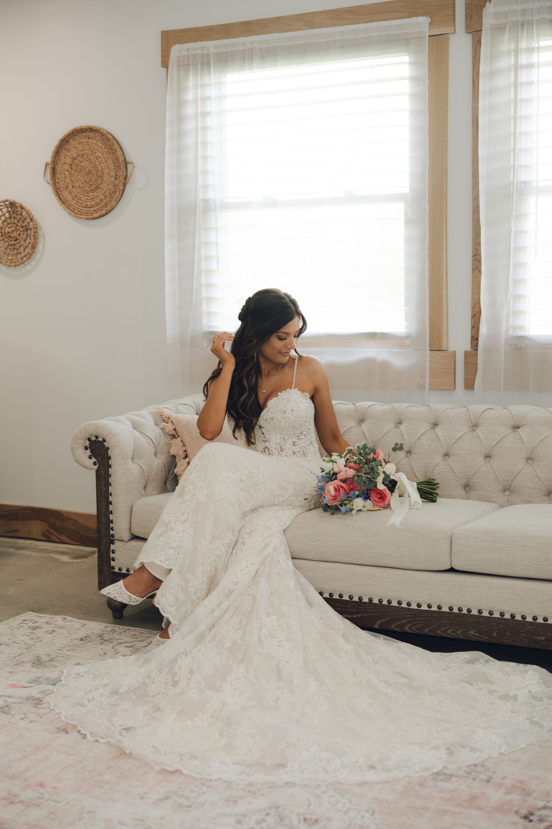 A bride in a wedding dress is sitting on a couch holding a bouquet of flowers.