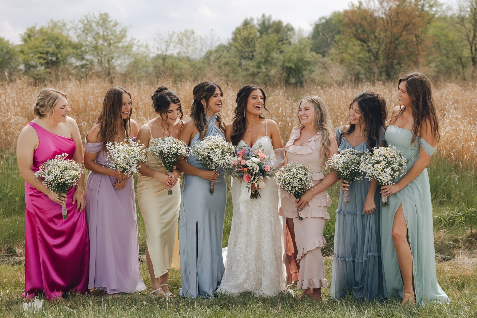 A bride and her bridesmaids are posing for a picture in a field.
