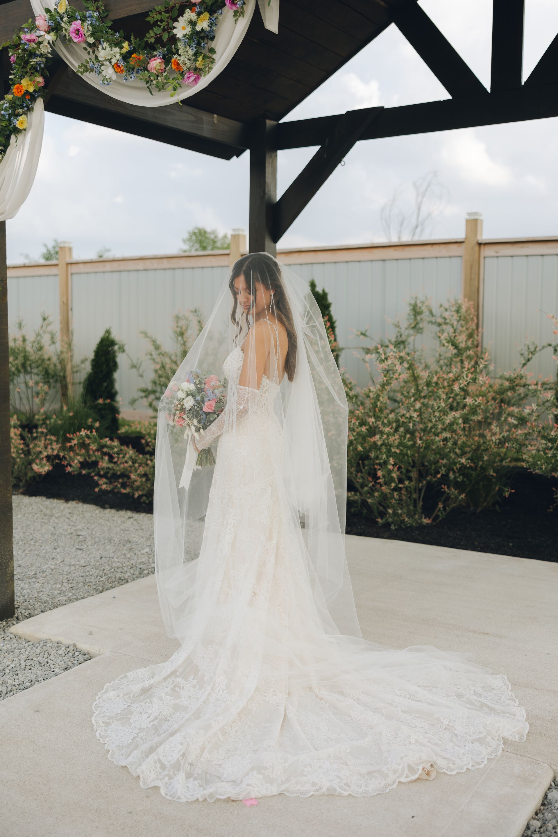 The bride is wearing a long veil and holding a bouquet of flowers.