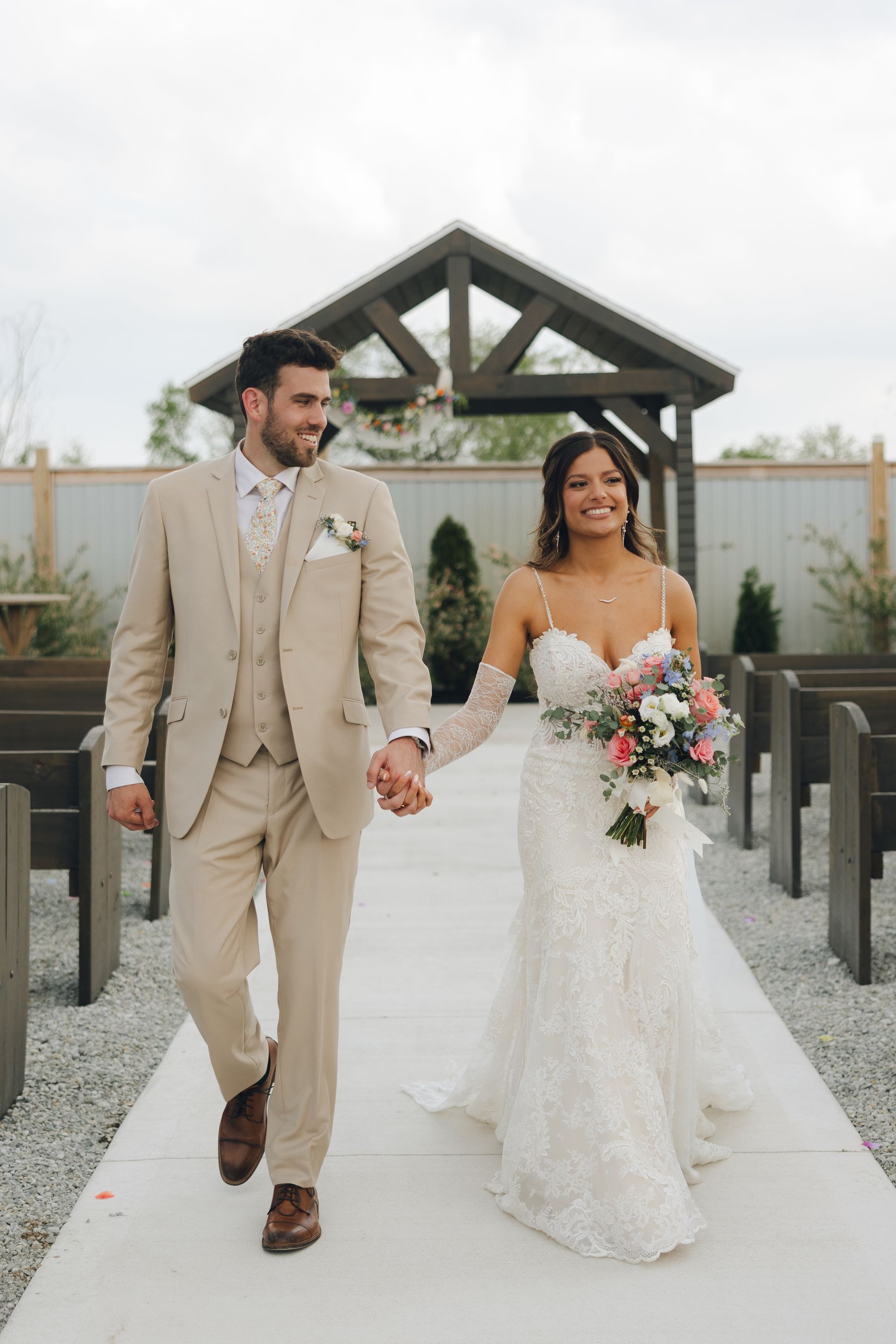 A bride and groom are walking down the aisle holding hands.