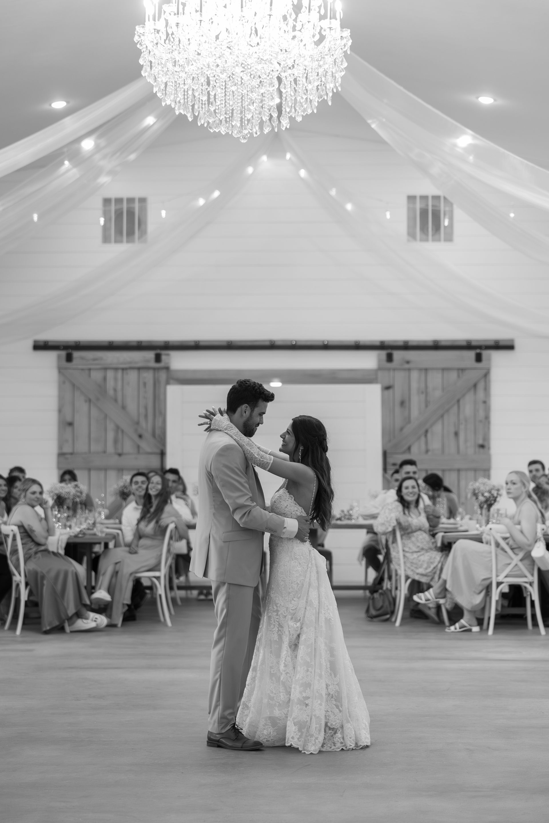 A black and white photo of a bride and groom dancing at their wedding reception.