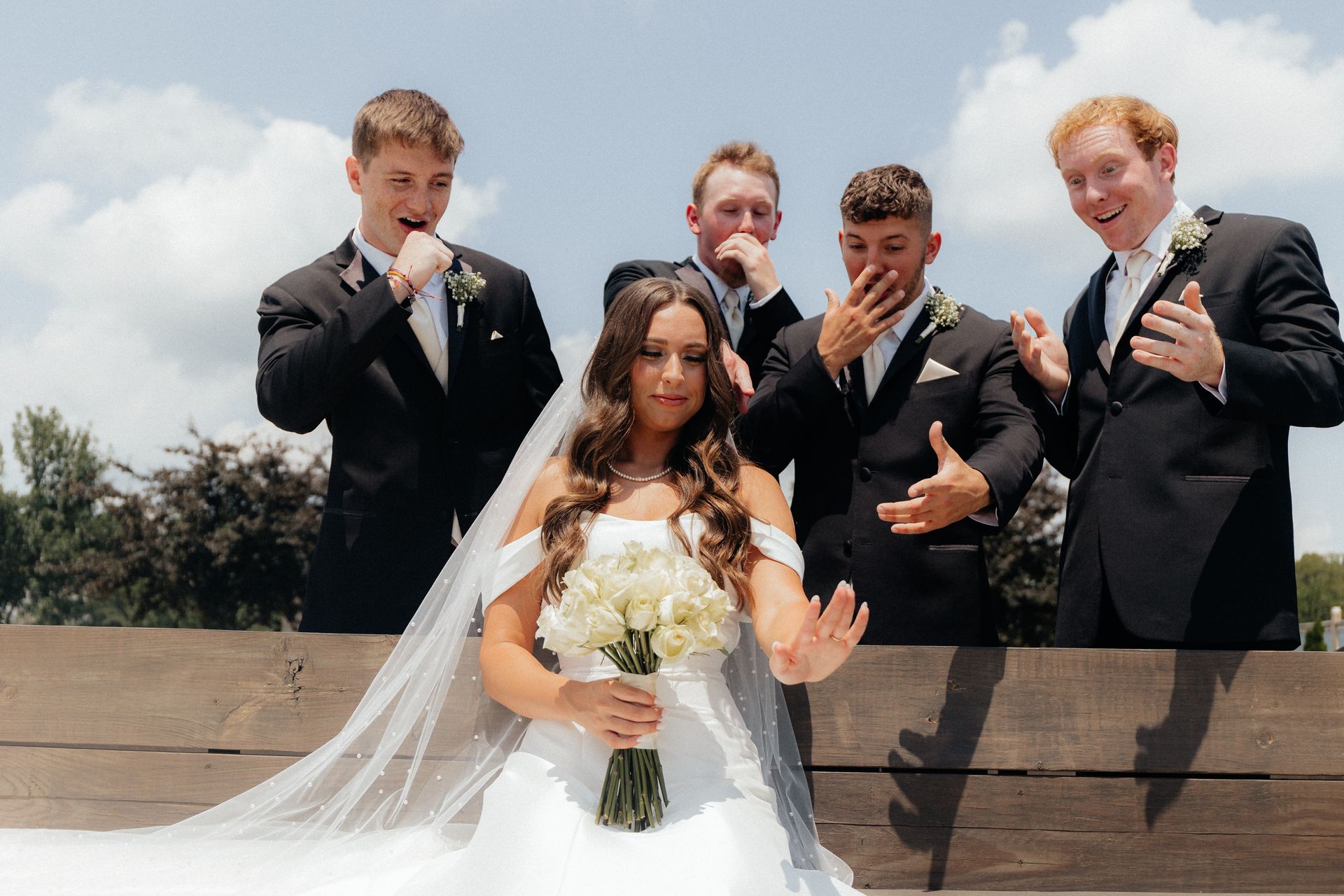 A bride and her groomsmen are posing for a picture.