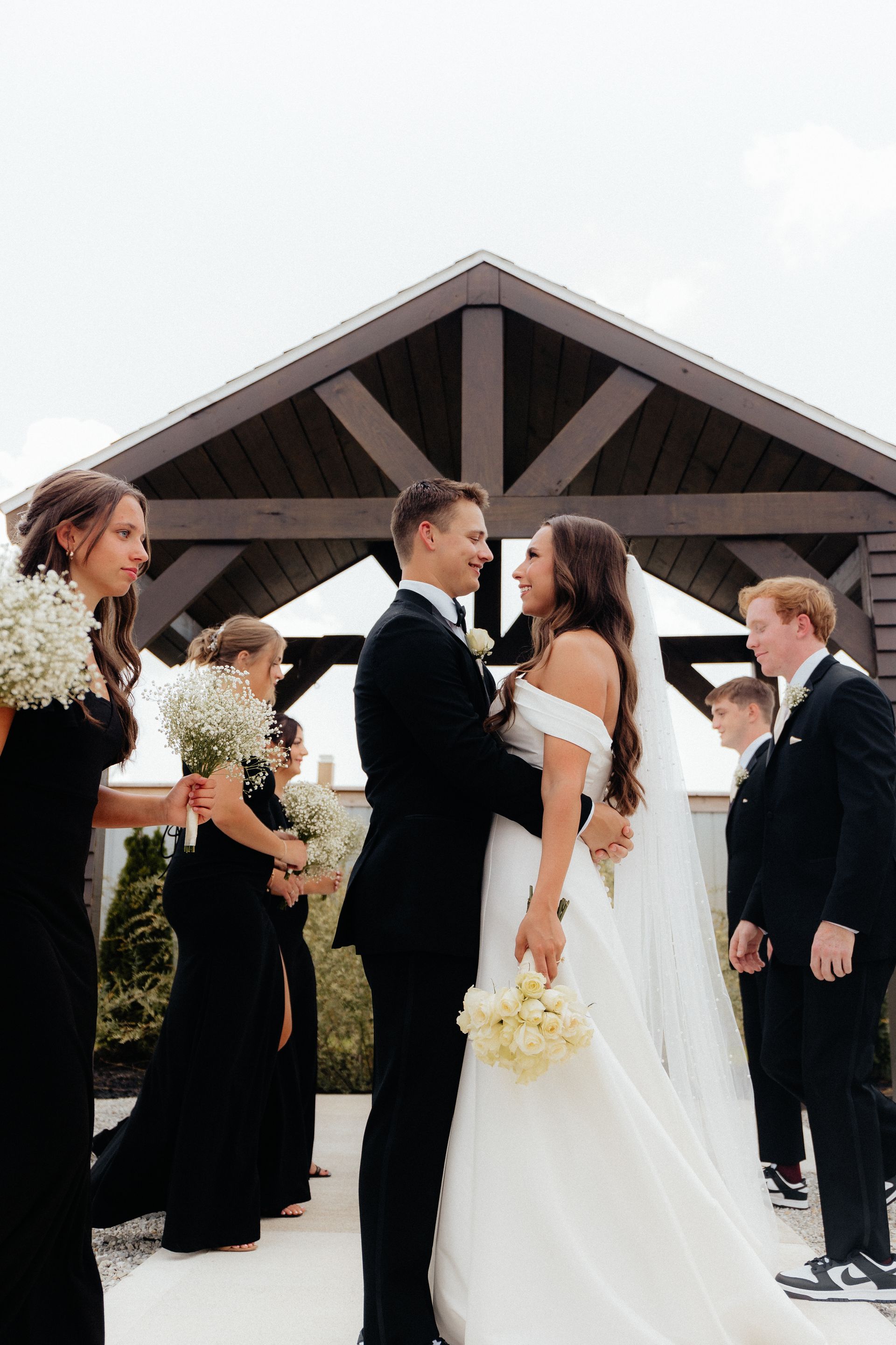 A bride and groom are kissing in front of their wedding party.