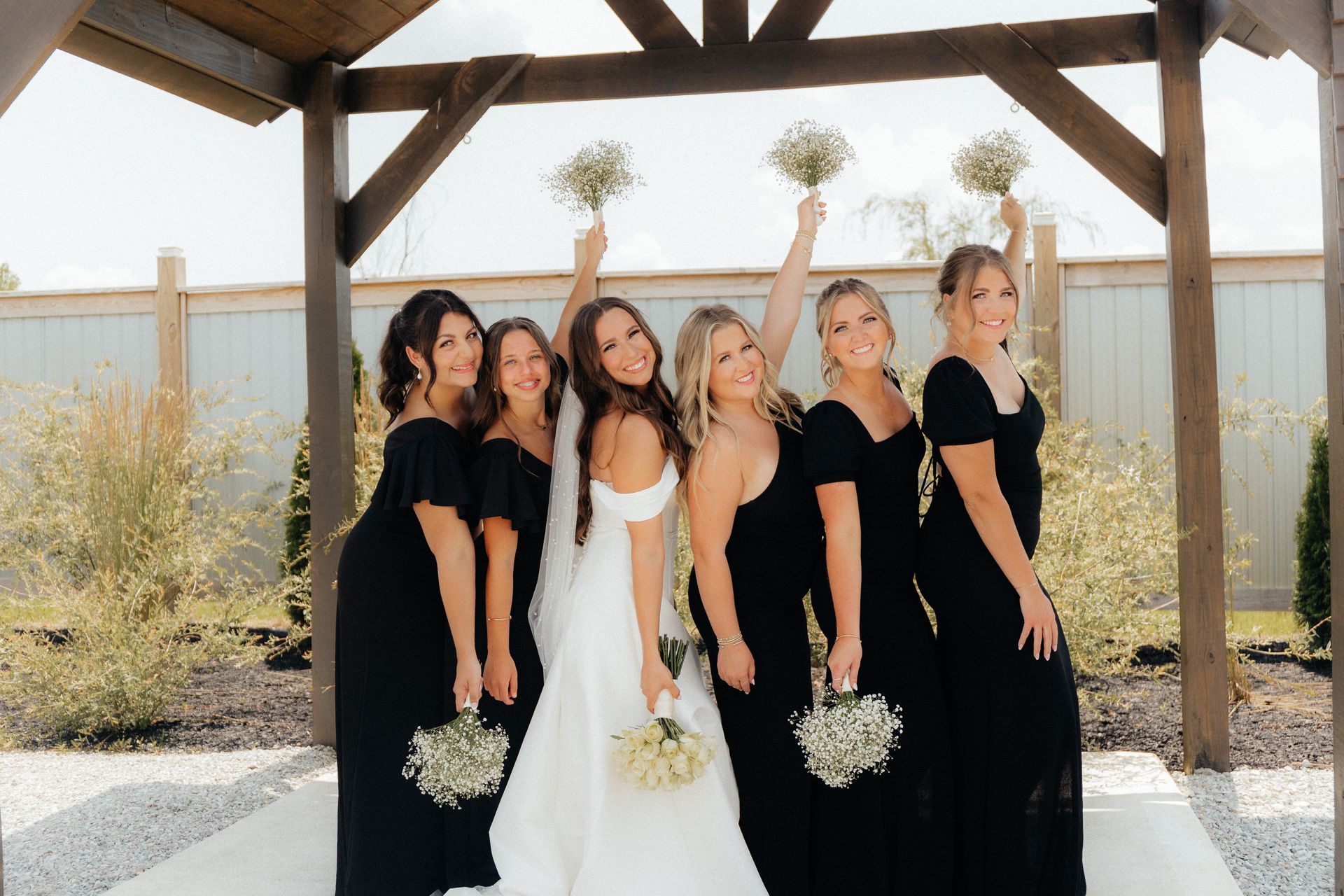 A bride and her bridesmaids are posing for a picture under a gazebo.