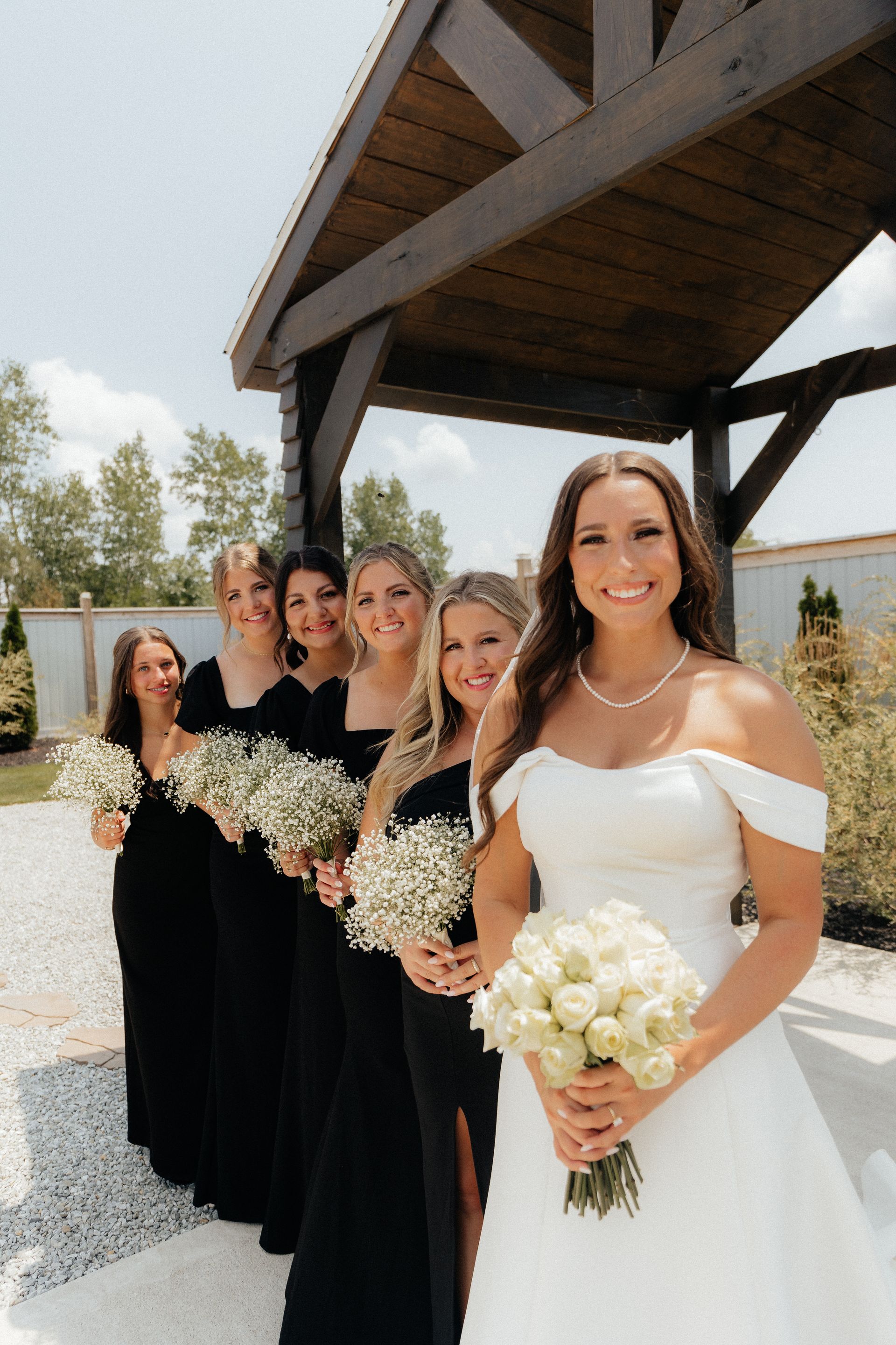 A bride and her bridesmaids are posing for a picture under a gazebo.