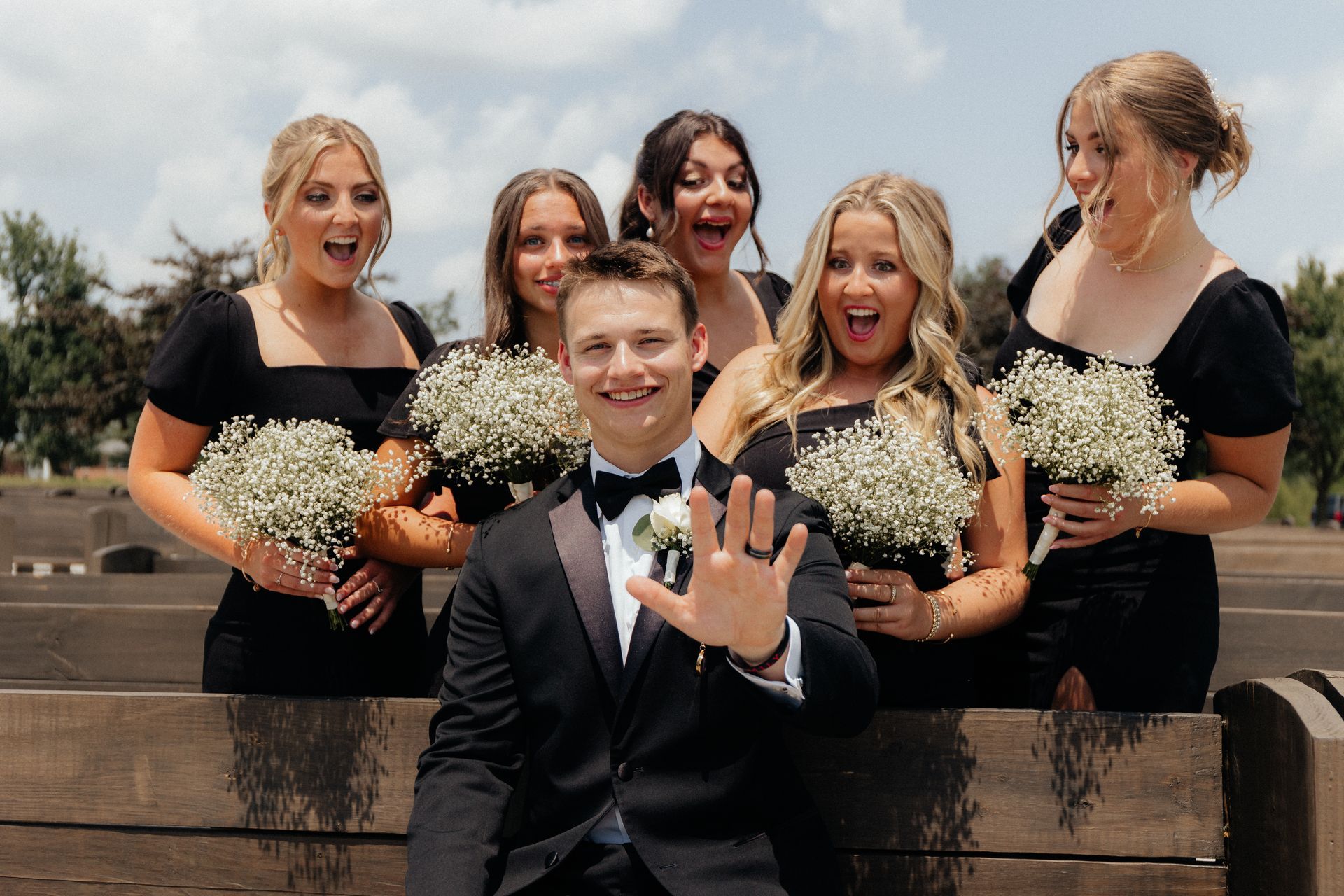 A bride and groom are posing for a picture with their bridesmaids.