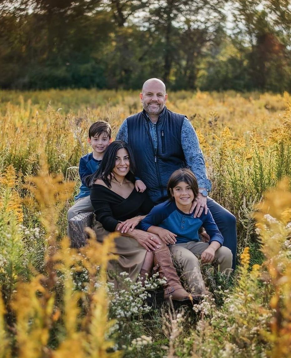 A family is posing for a picture in a field of flowers.