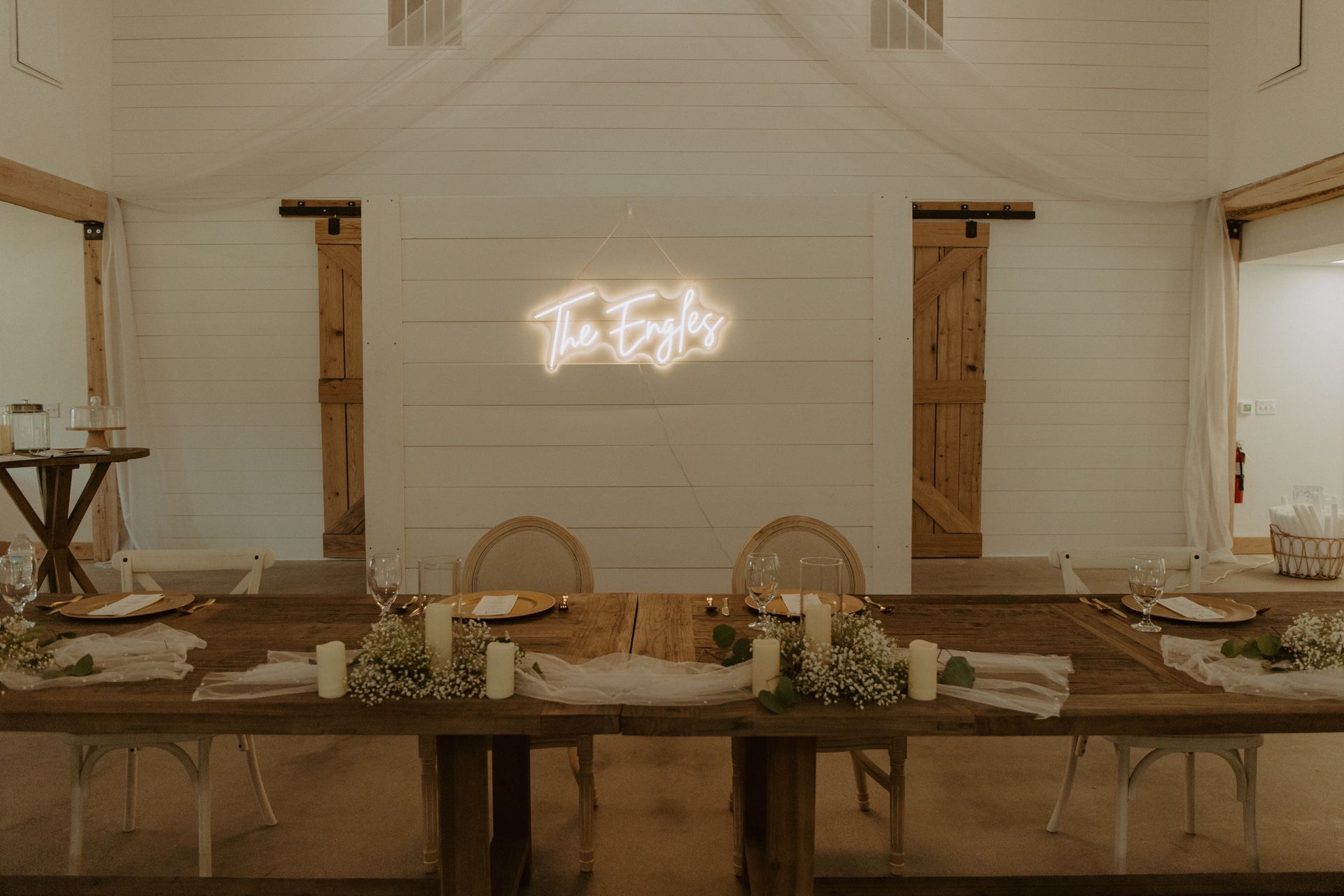 A long wooden table with a neon sign on the wall.