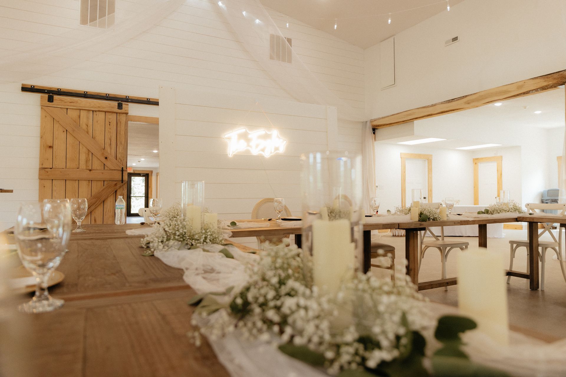 A long wooden table with candles and flowers on it in a room.