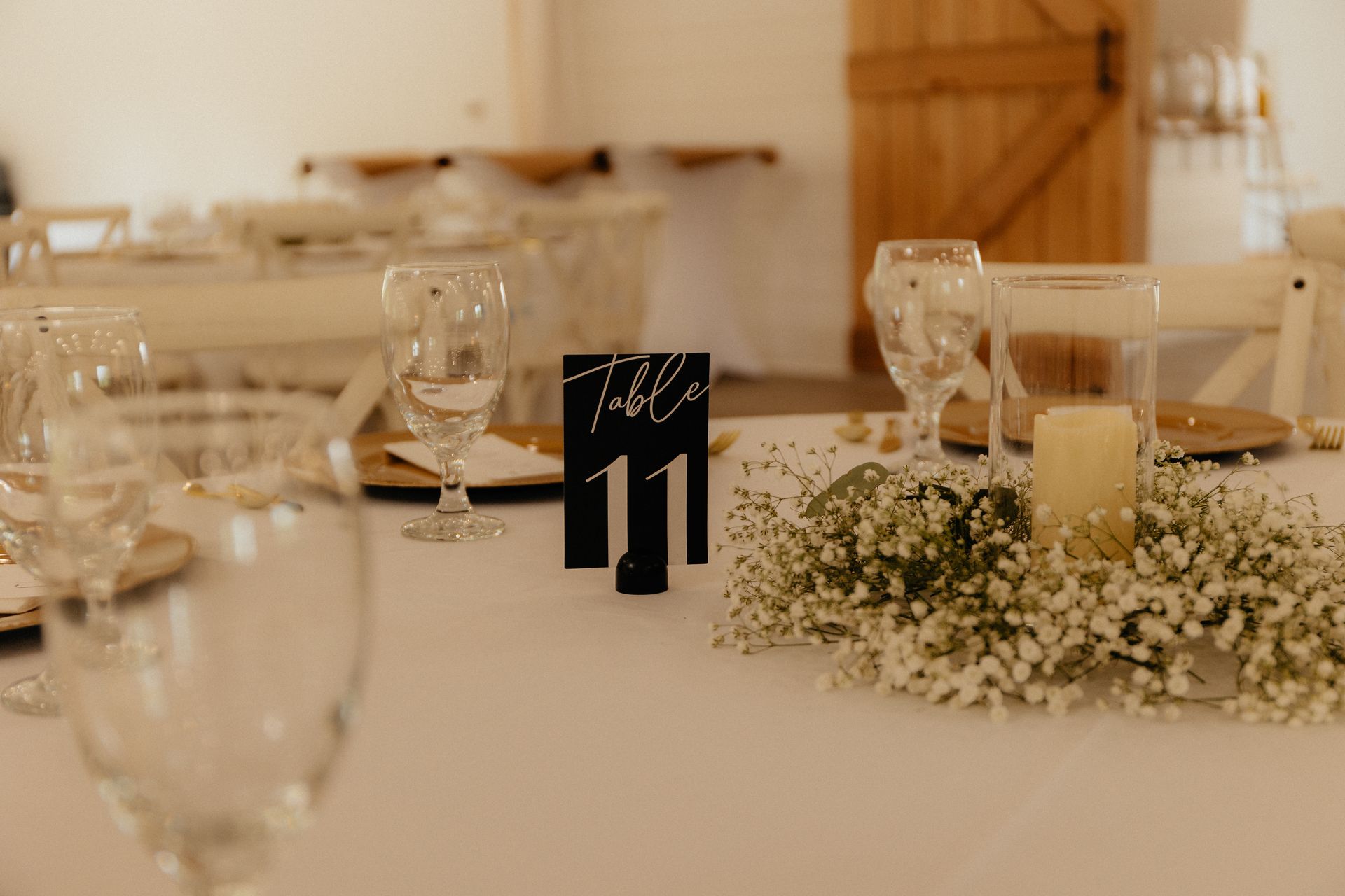 A table with glasses , candles , and baby 's breath on it.