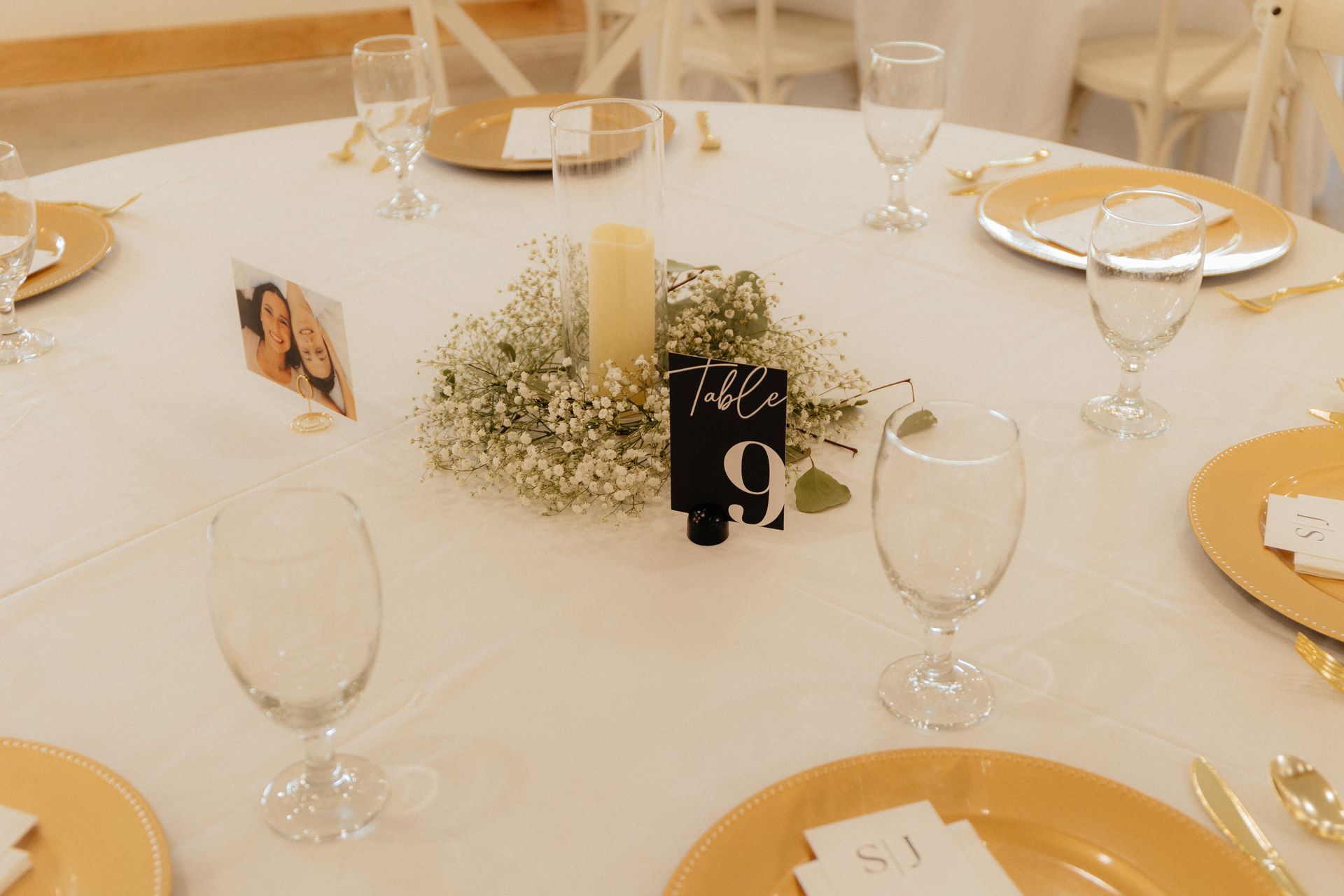 A table set for a wedding reception with plates , glasses , and a table number.