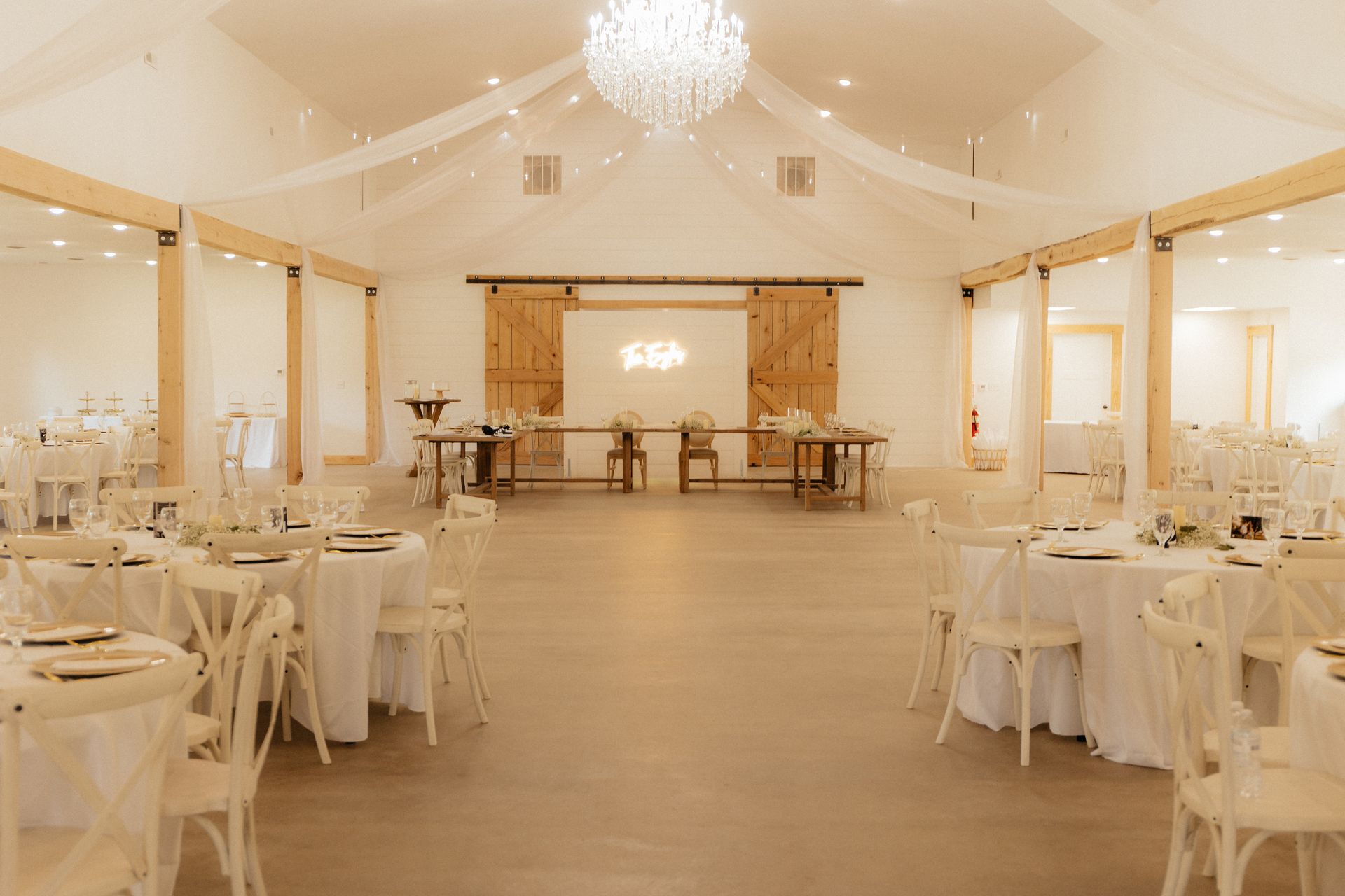 A large room with tables and chairs set up for a wedding reception.