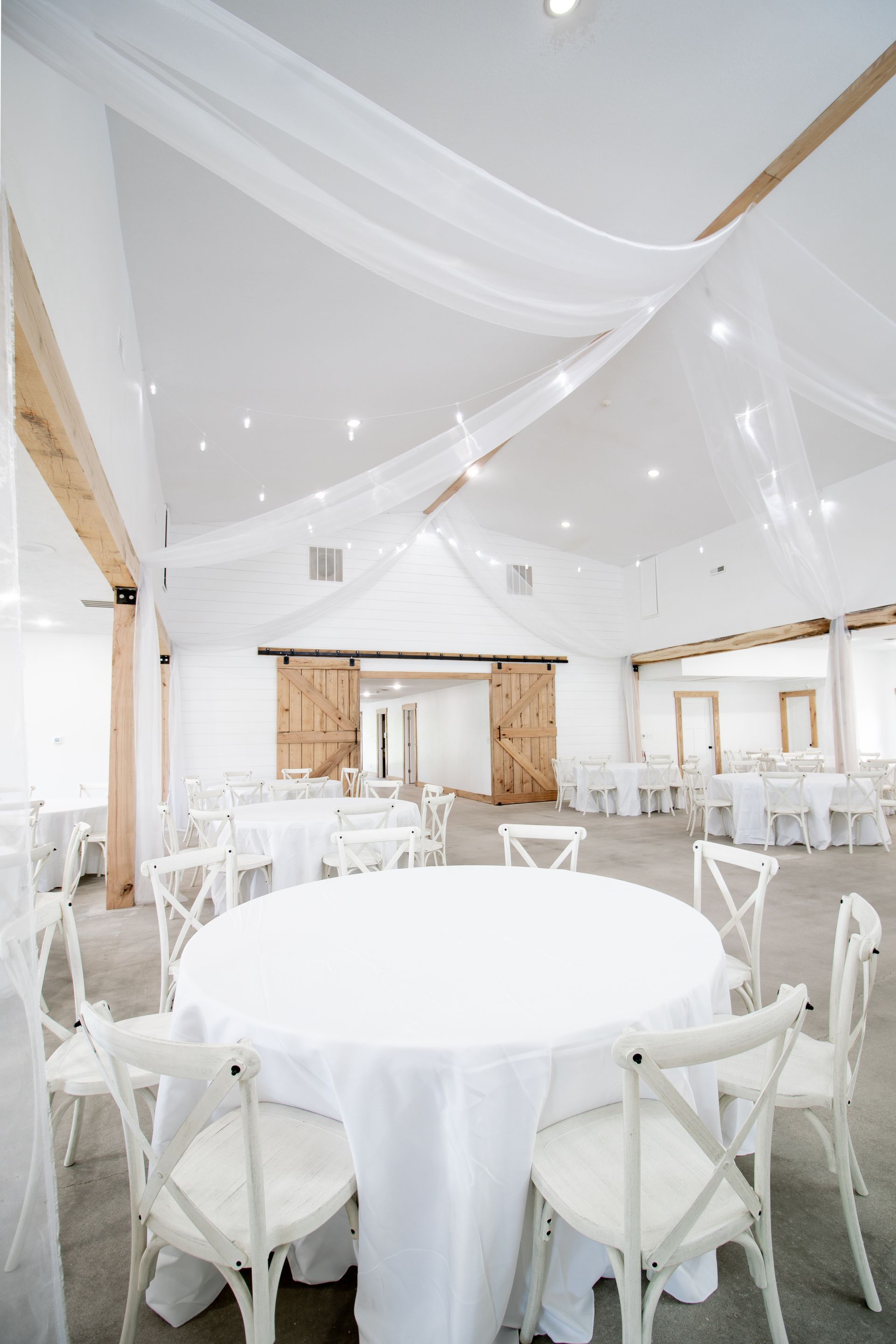 A large room with tables and chairs set up for a wedding reception.
