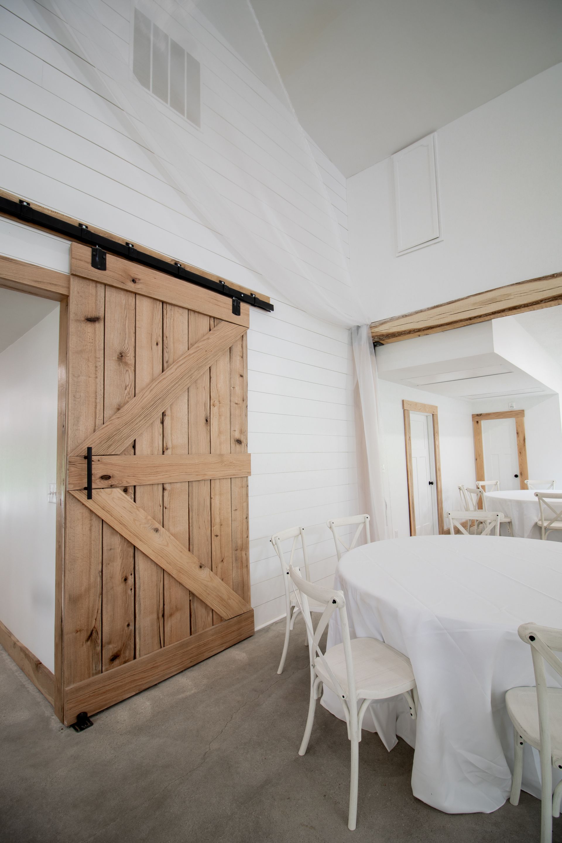 A dining room with a table and chairs and a sliding barn door.