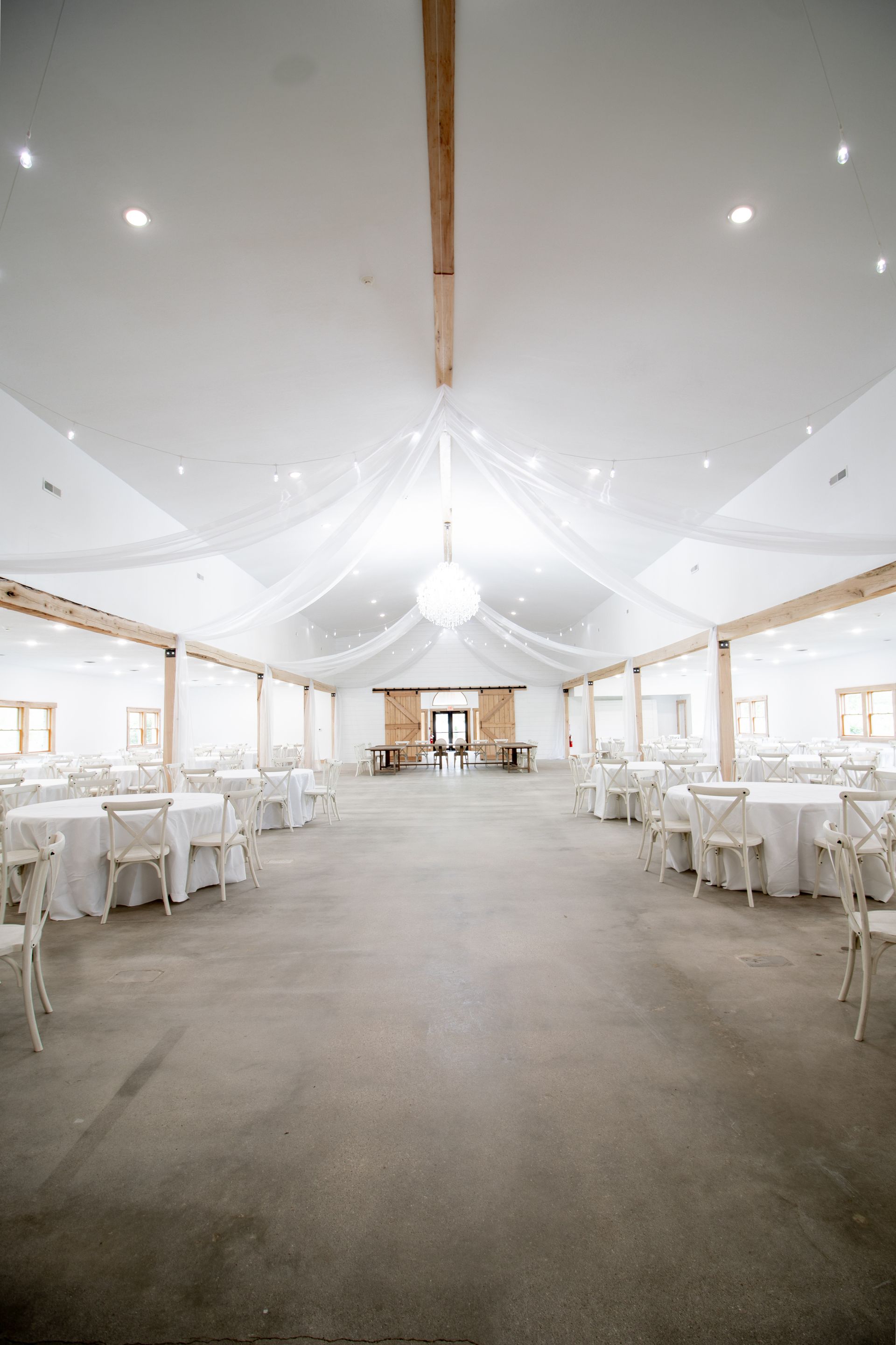 A large room with tables and chairs set up for a wedding reception.