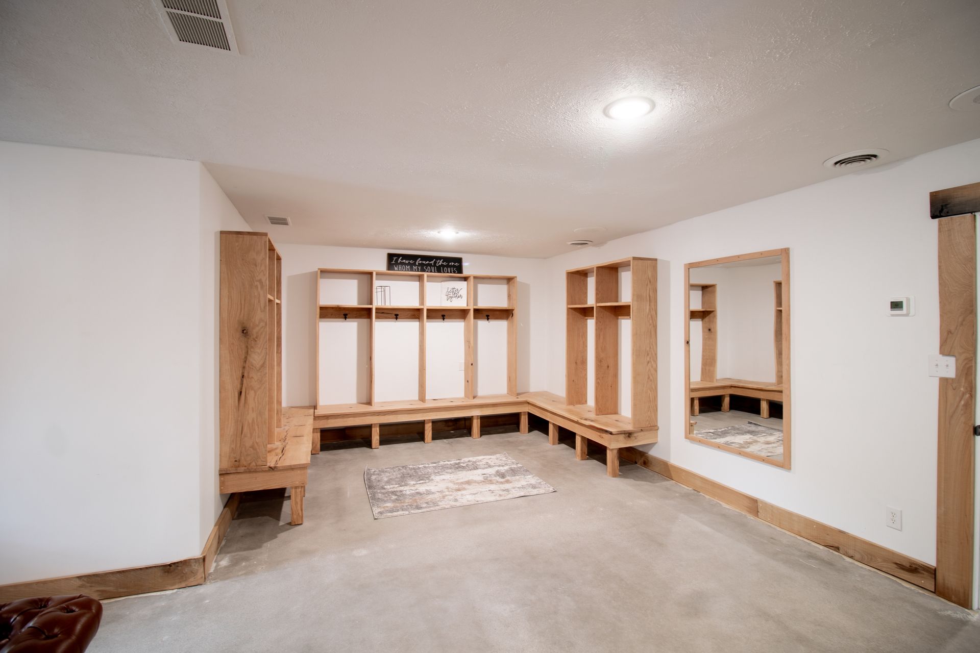 A locker room with wooden shelves , benches and mirrors.