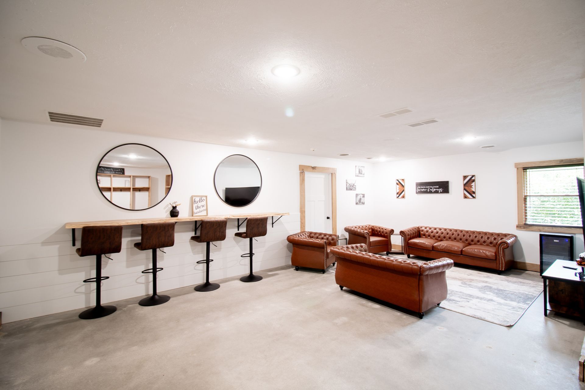 A living room with a couch , chairs , a table and a mirror.