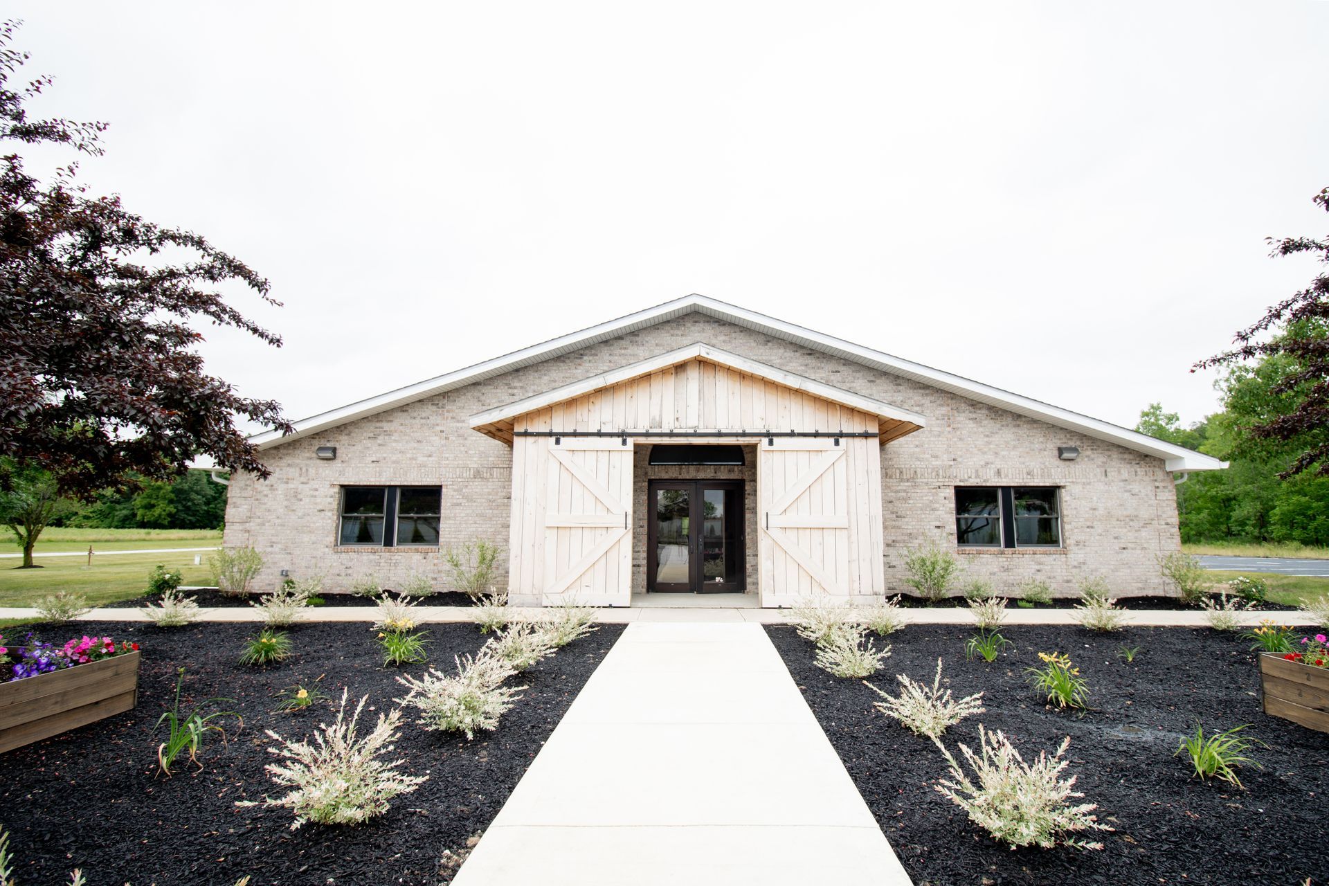A large brick building with a sliding barn door and a walkway leading to it.